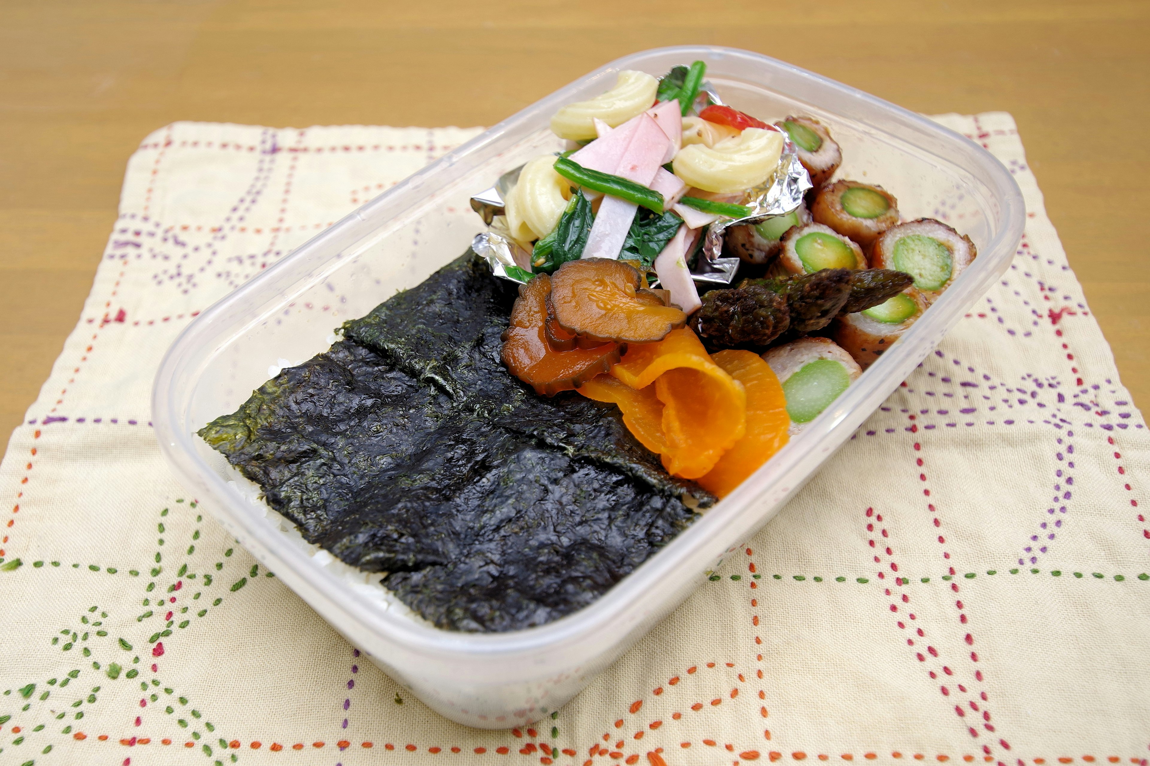 A bento box featuring layered seaweed and assorted vegetables