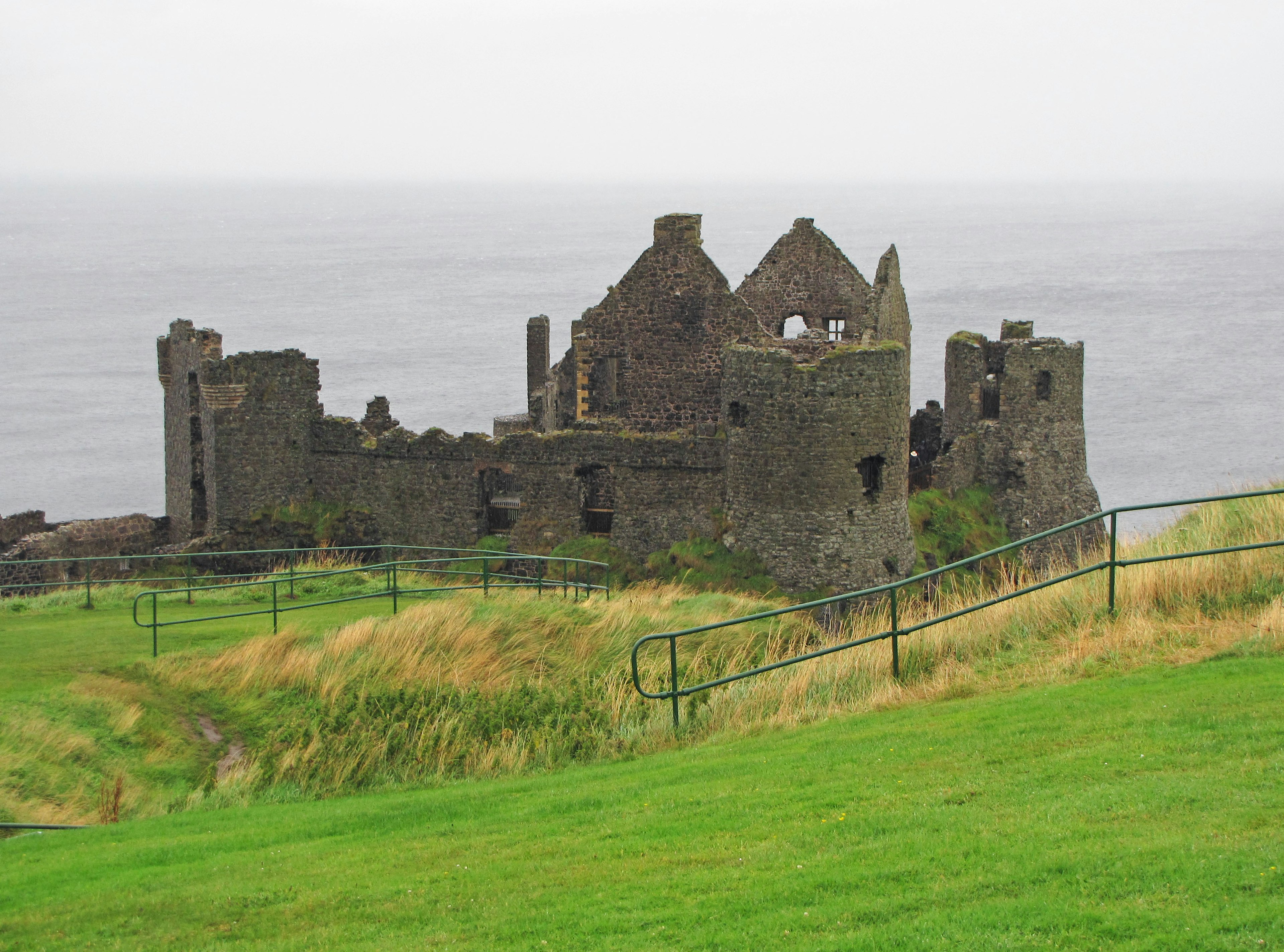 Ruinas de un viejo castillo con vista al mar rodeado de hierba verde