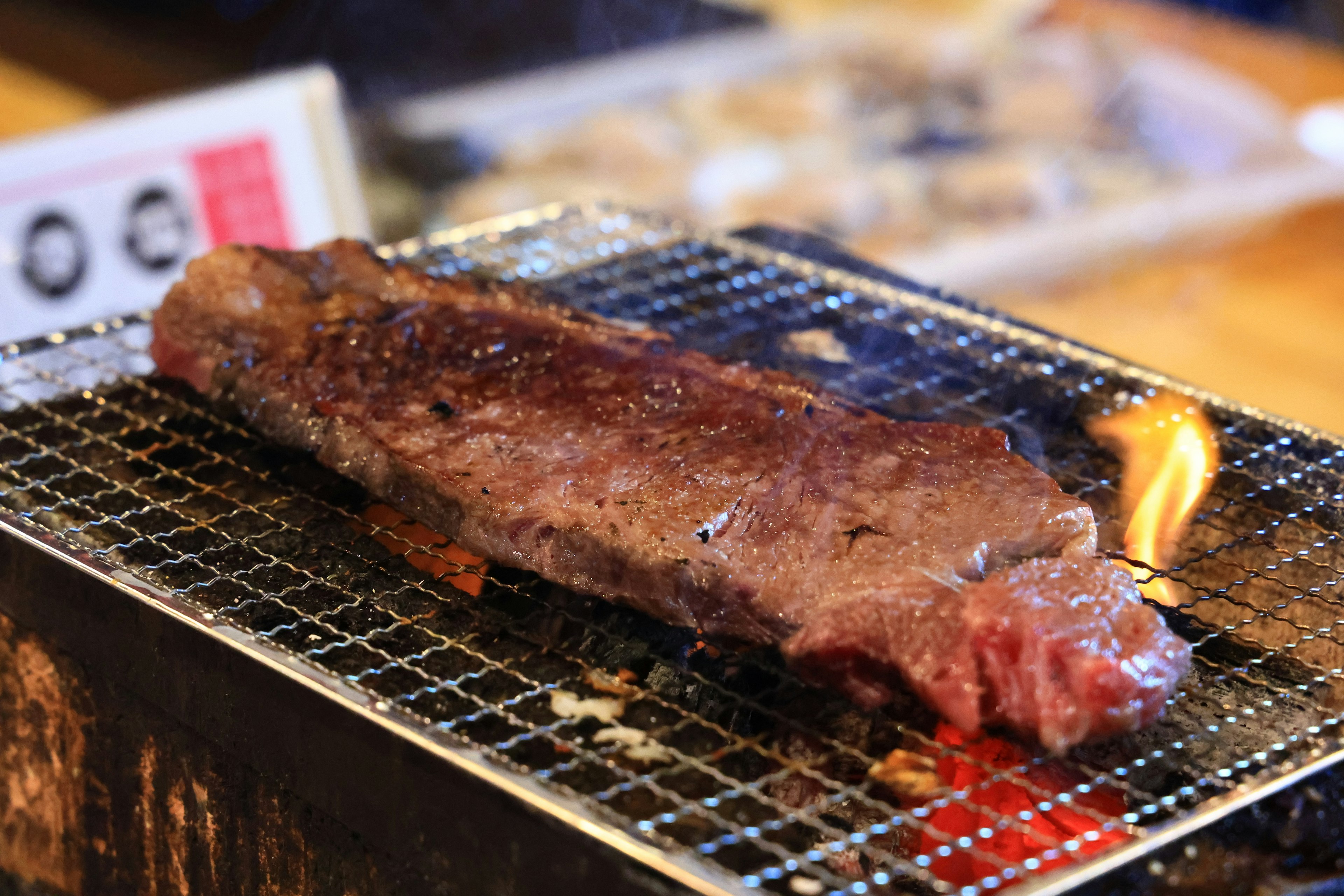 Gegrillte Fleischscheibe, die über Kohlenflammen gart