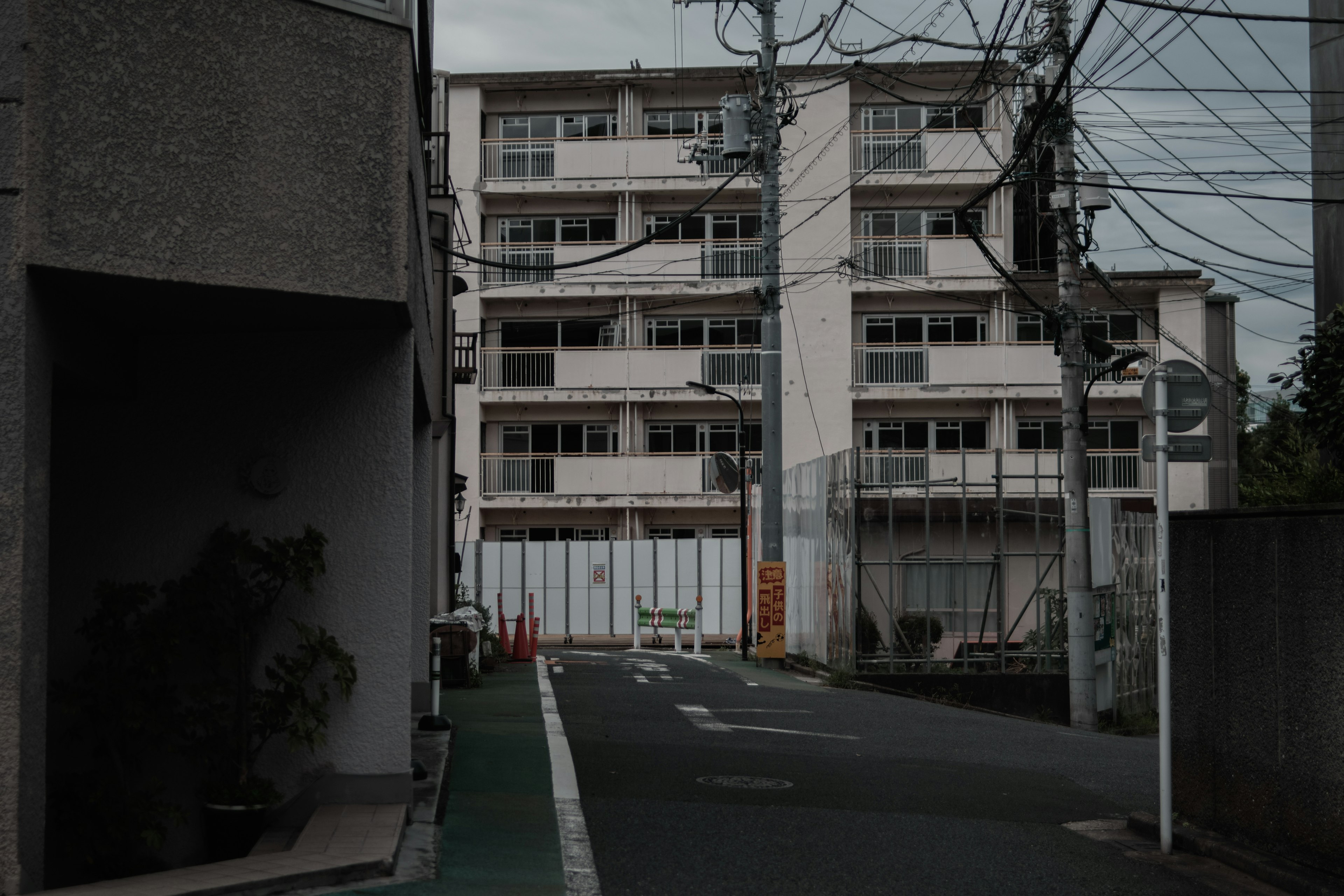 薄暗い路地に囲まれた住宅の外観