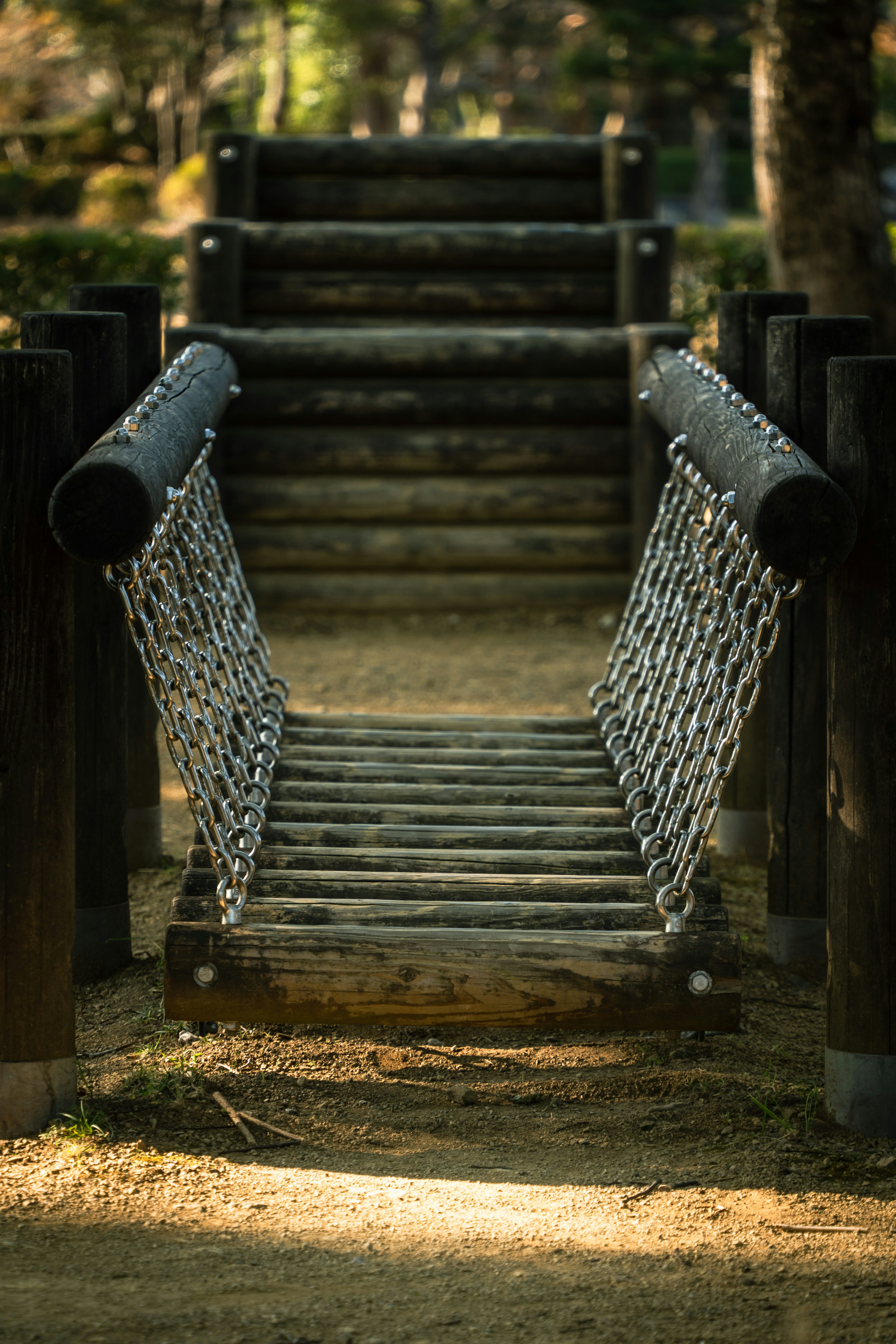 Puente de cadena en un parque infantil hecho de postes de madera y cadenas de metal