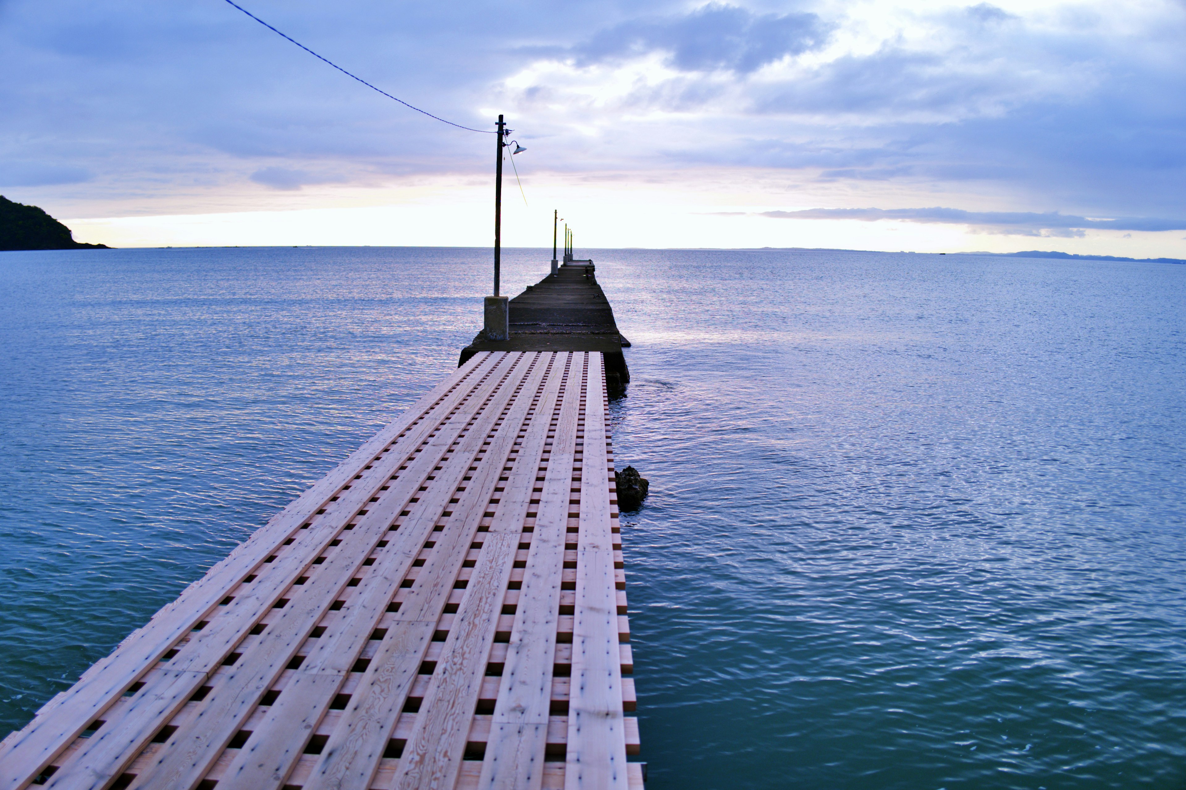 Muelle de madera que se extiende en aguas tranquilas bajo un cielo azul