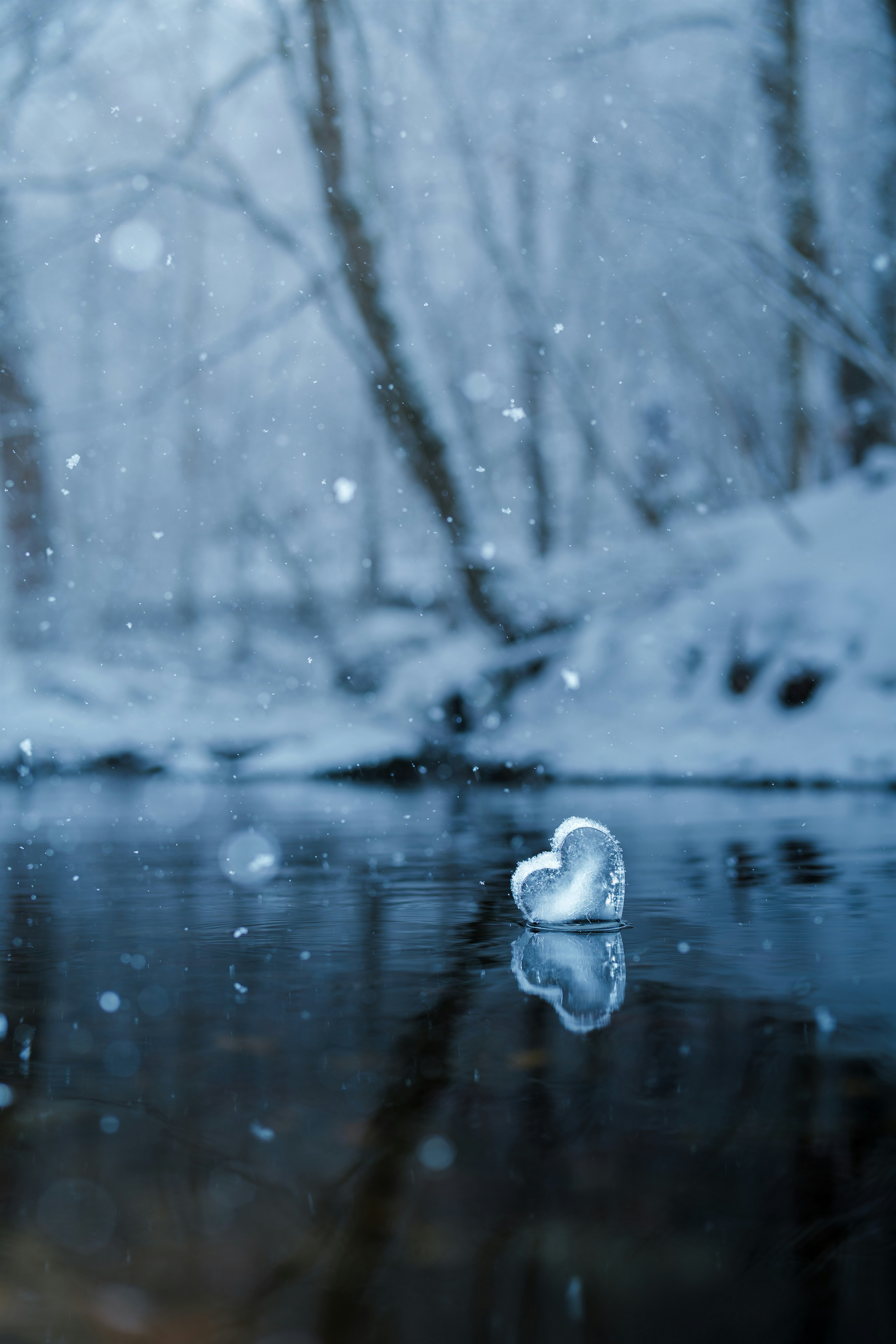 Un cuore di ghiaccio che galleggia su un fiume tranquillo circondato dalla neve