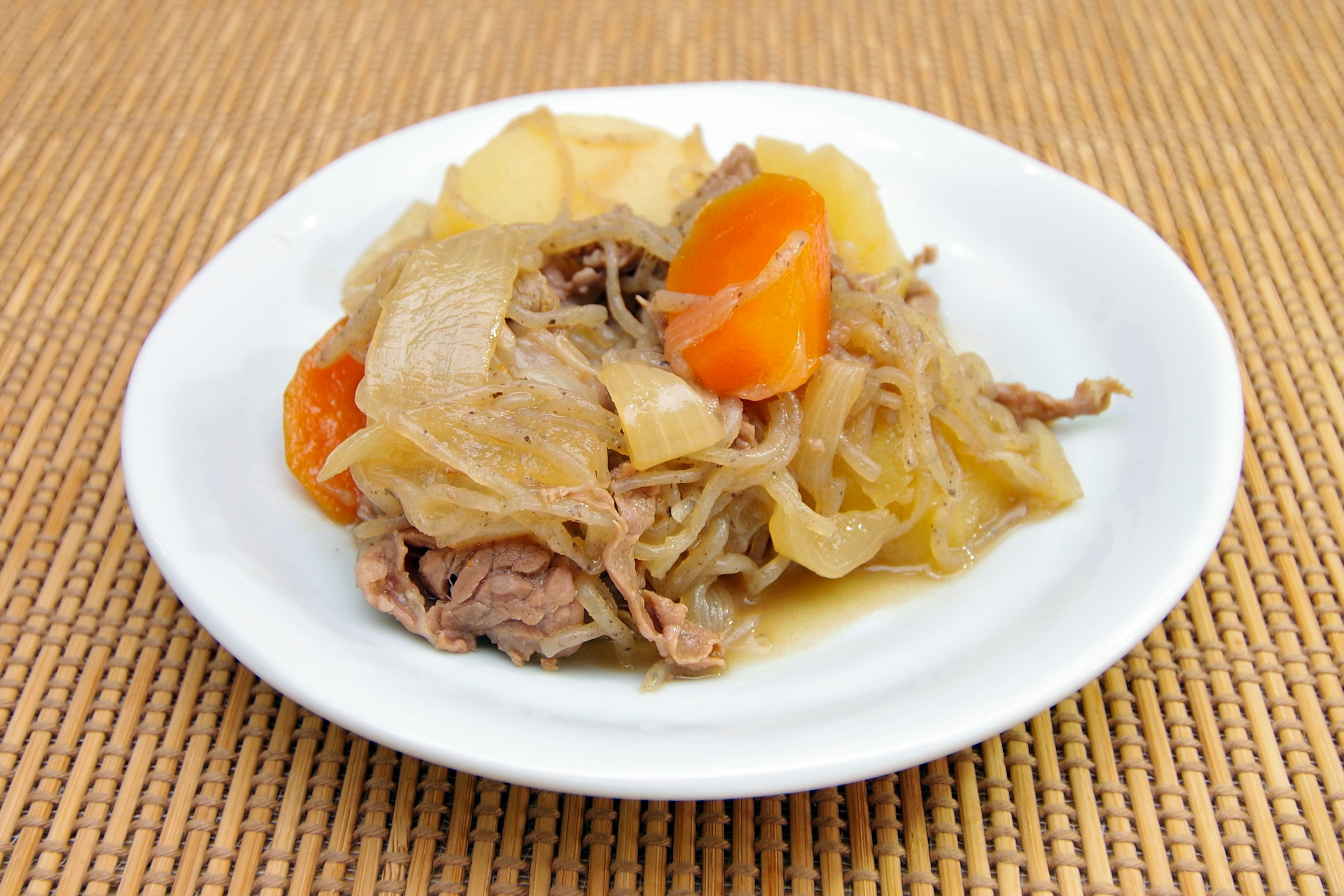 A plate of simmered meat and vegetables in a white dish