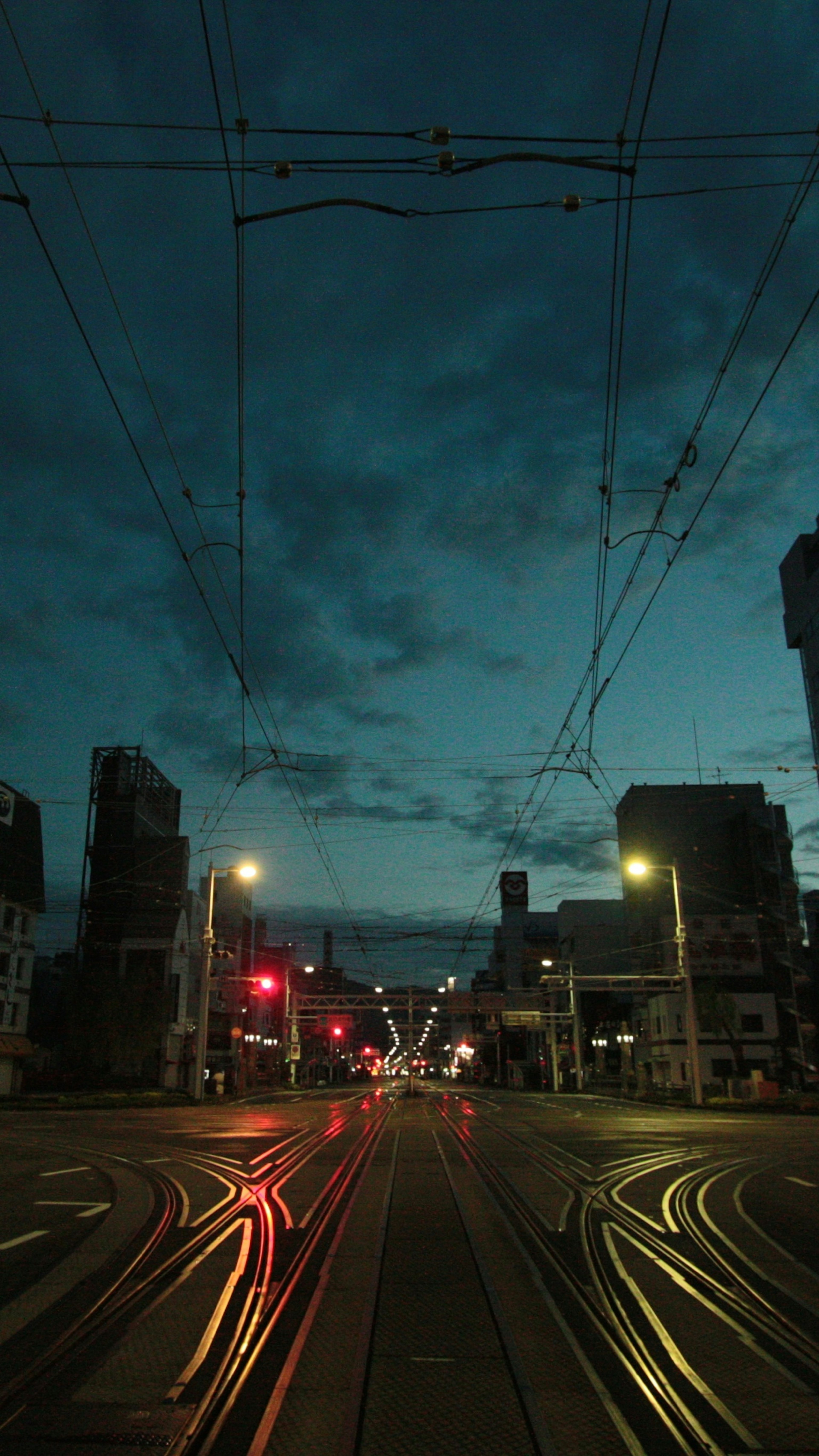 Intersección nocturna con rieles de tranvía y semáforos