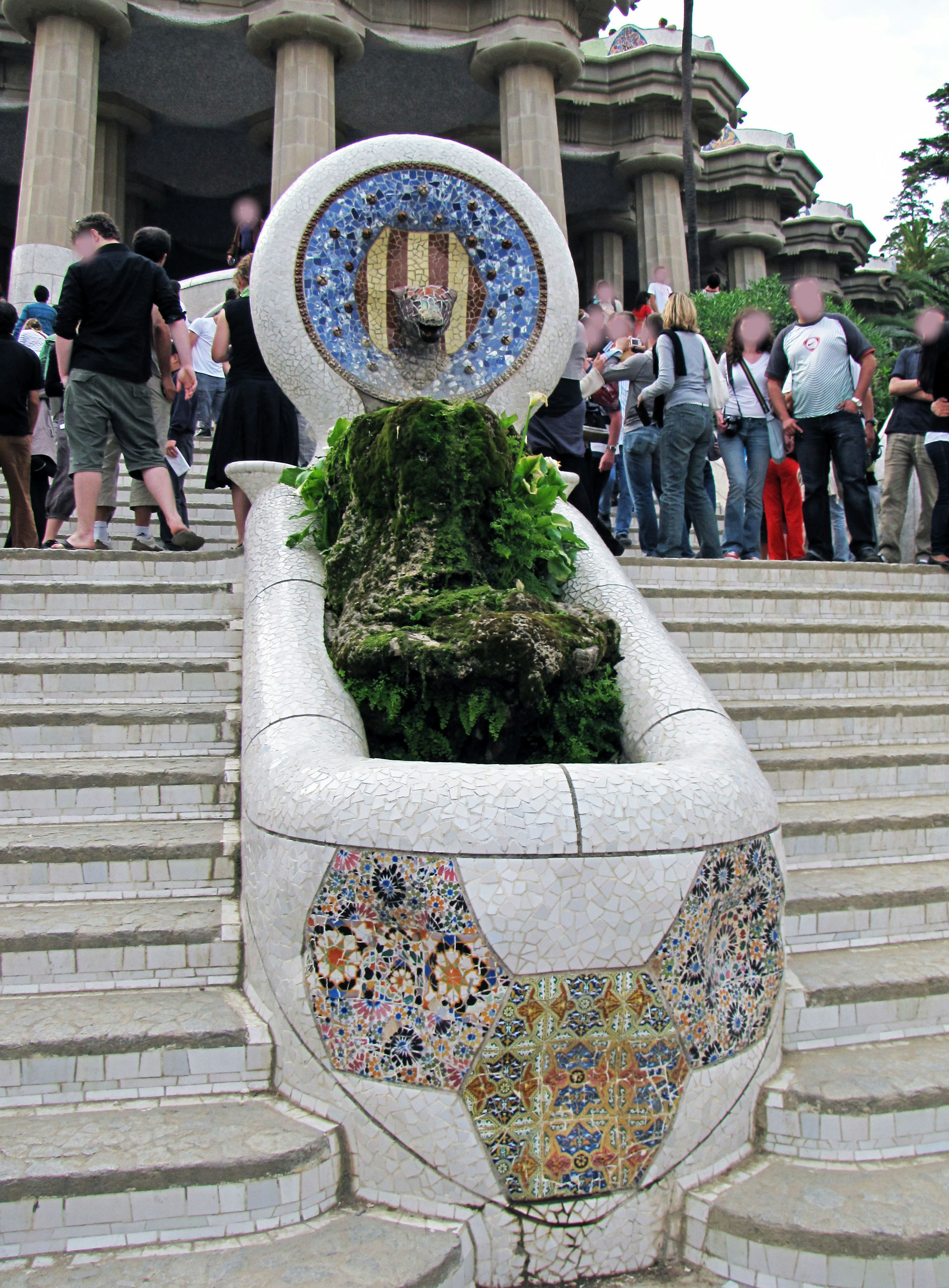 Fuente con hermosa decoración de mosaico y vegetación exuberante en una escalera de parque