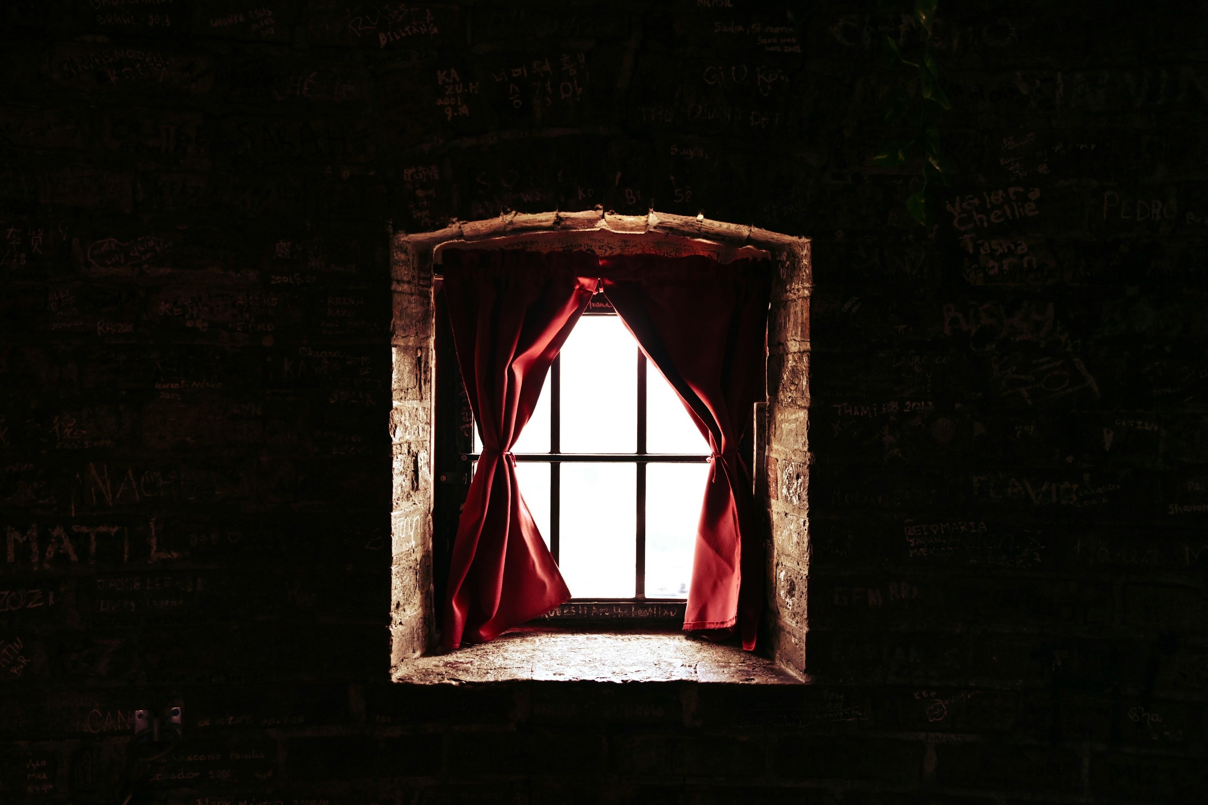 Image d'une fenêtre avec des rideaux rouges sur un mur sombre