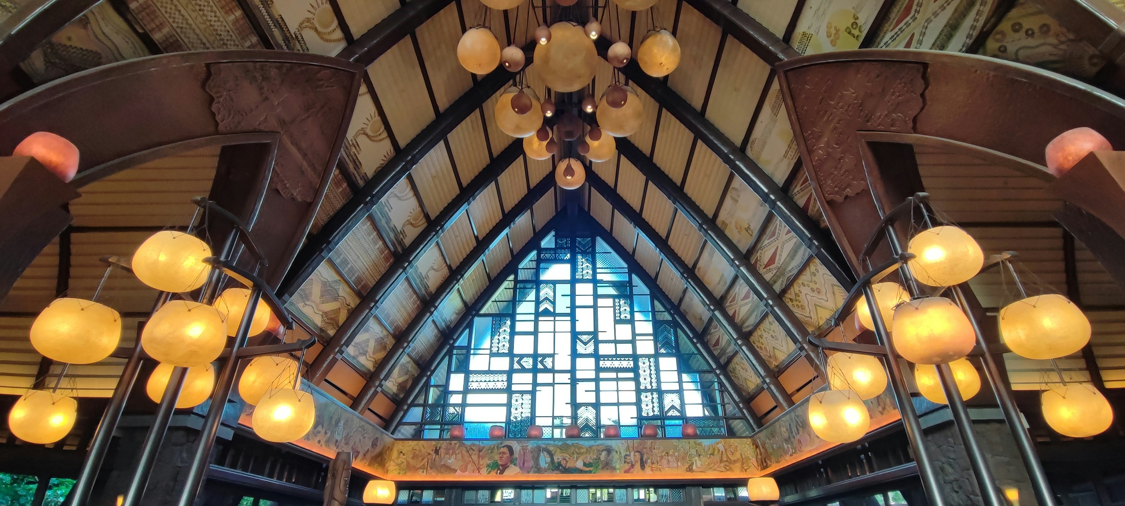 Intérieur d'un bâtiment avec un plafond haut présentant une structure en arc et de grandes fenêtres avec des lampes lumineuses