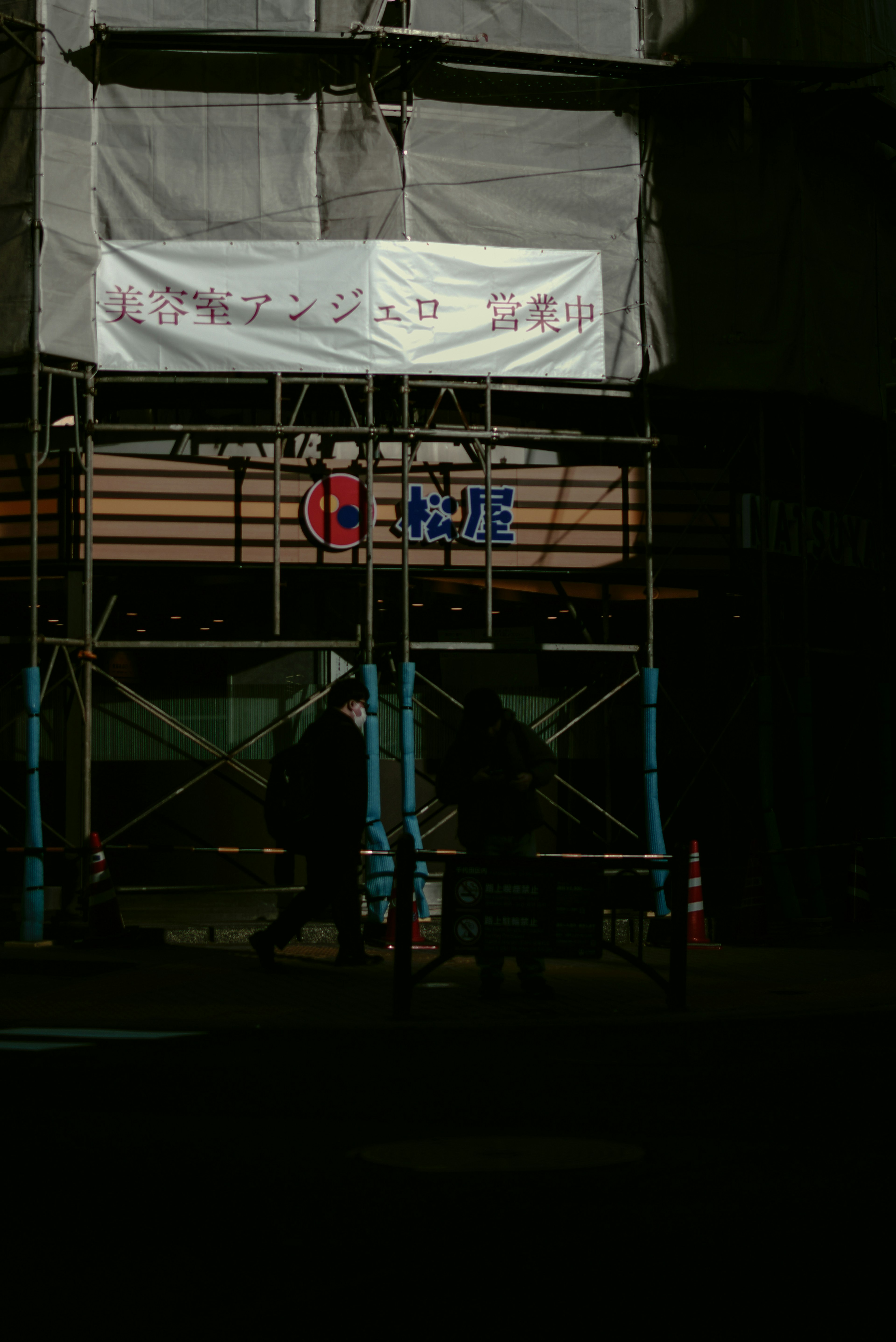 Calle oscura con andamios de construcción y cartel