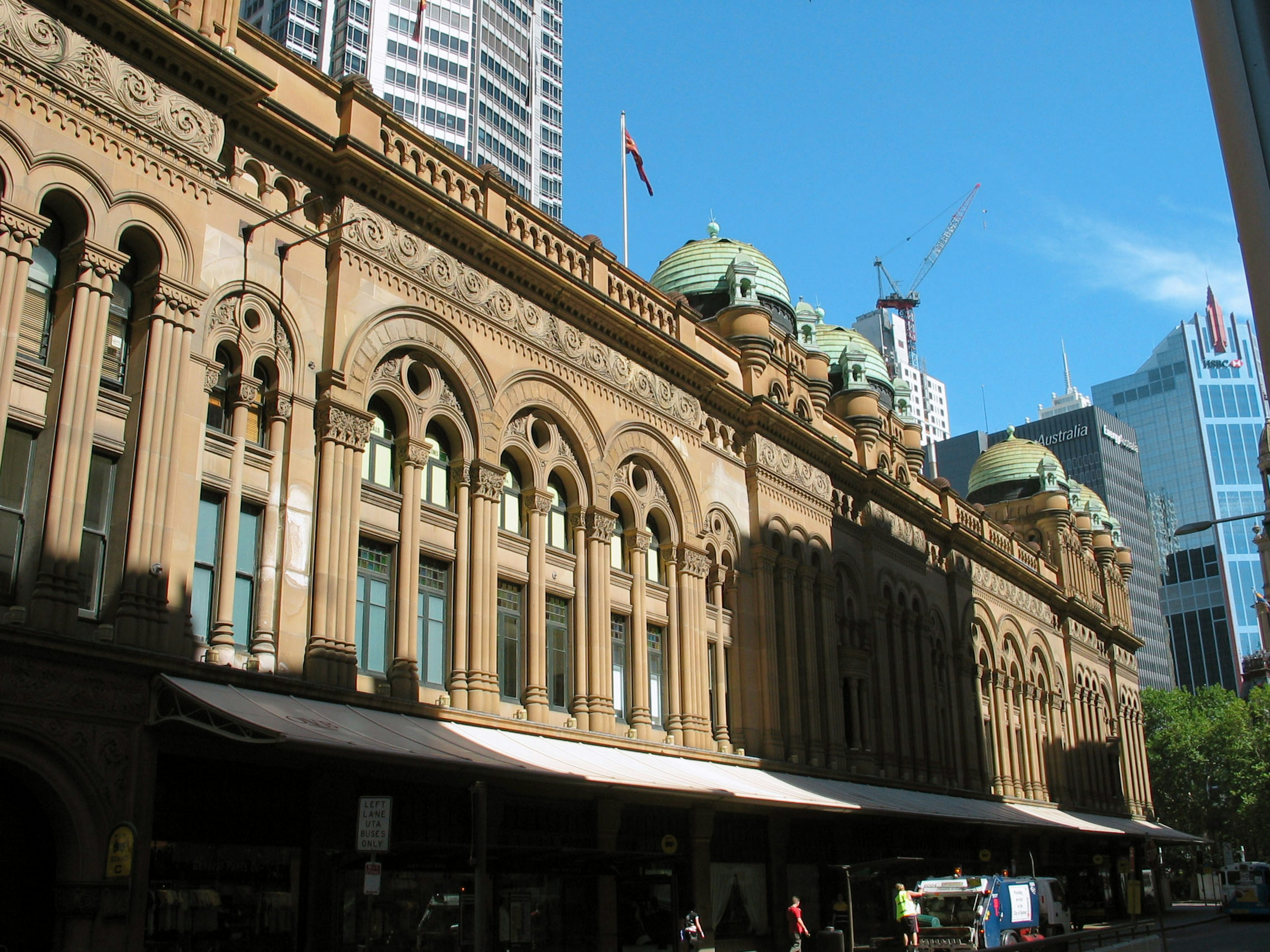 Exterior view of a historic building in Sydney featuring arched windows and green domes under a blue sky