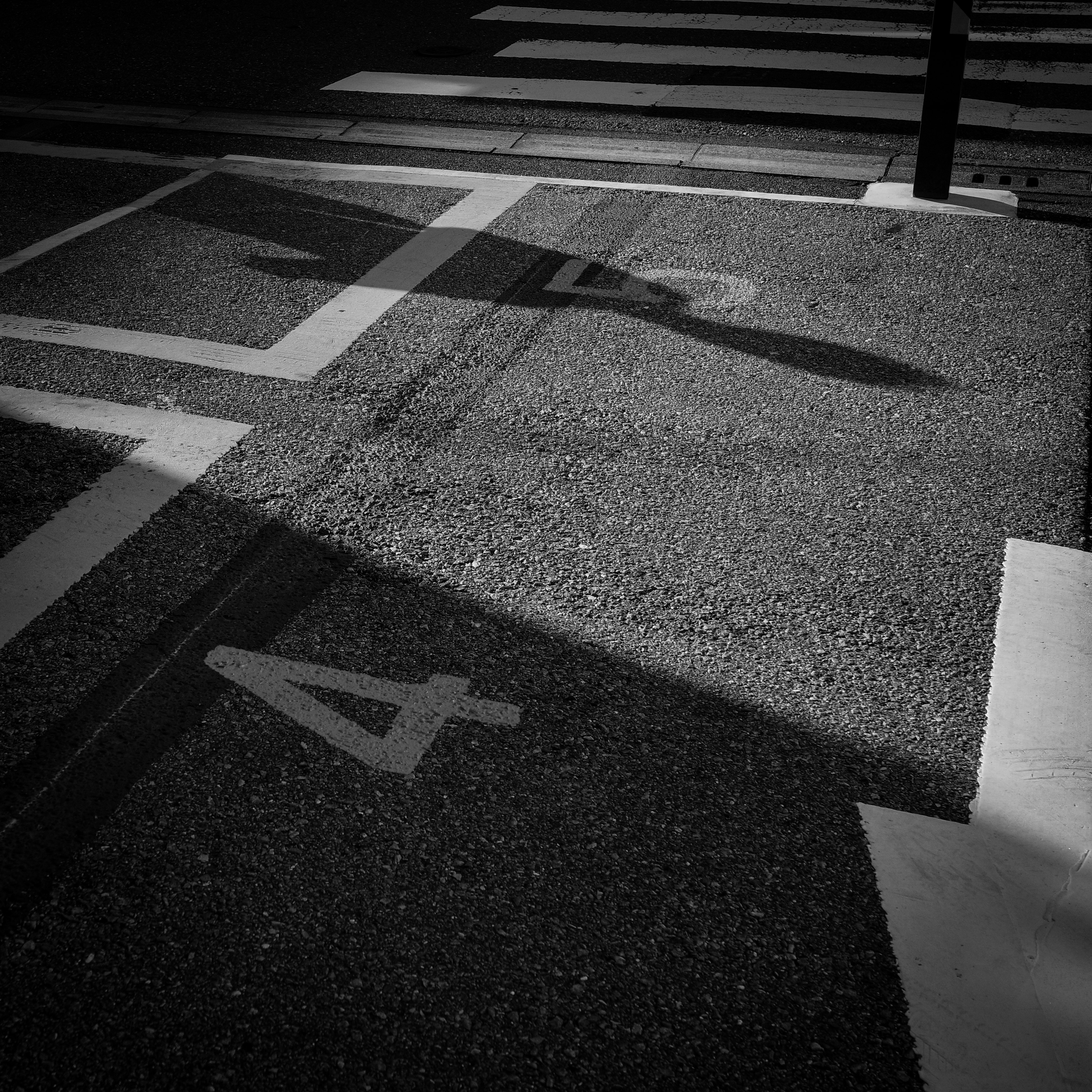 Black and white image of a parking space with shadows cast on the pavement