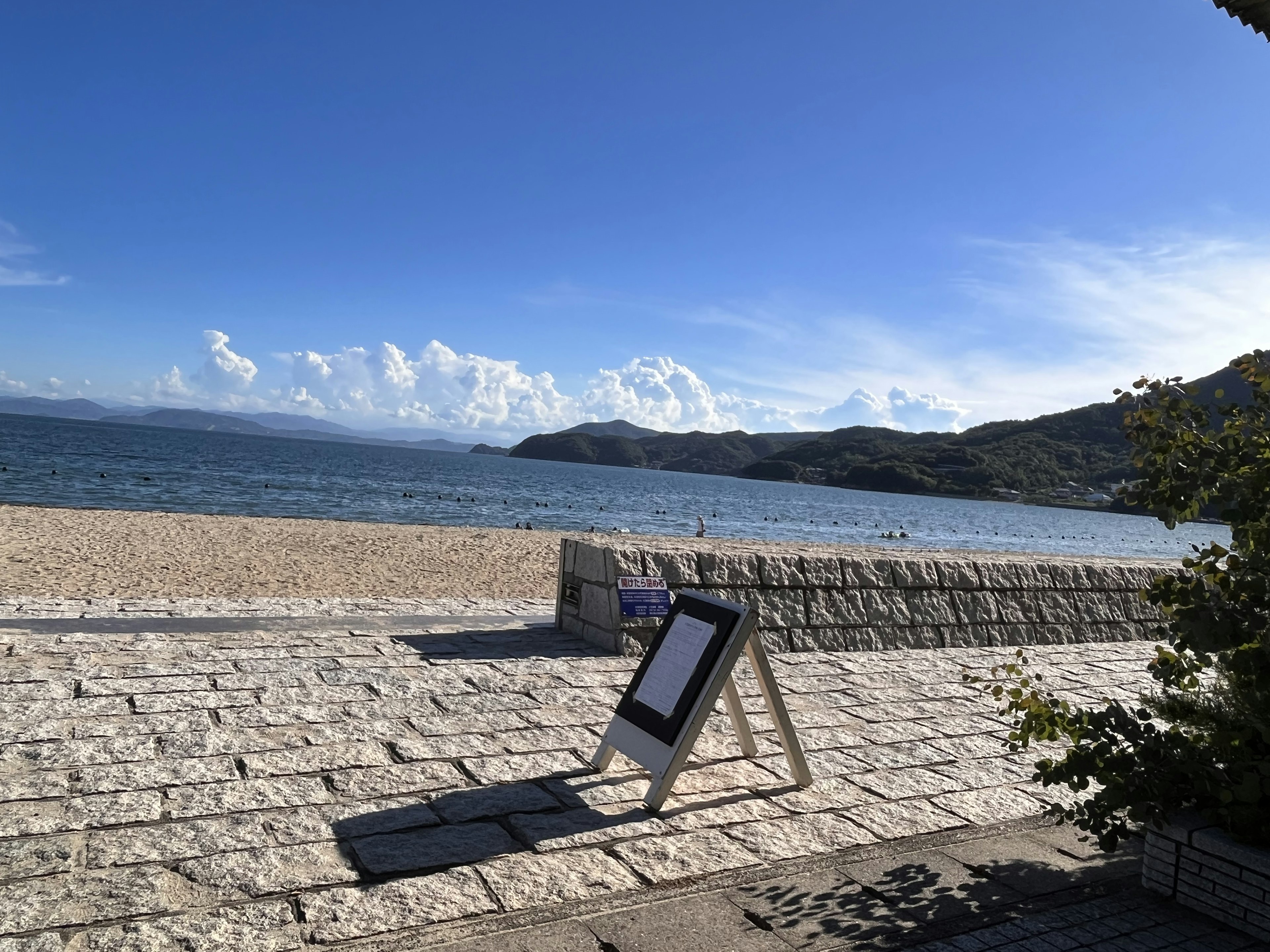 海辺の風景に立つ看板とストーンウォールの前のビーチ