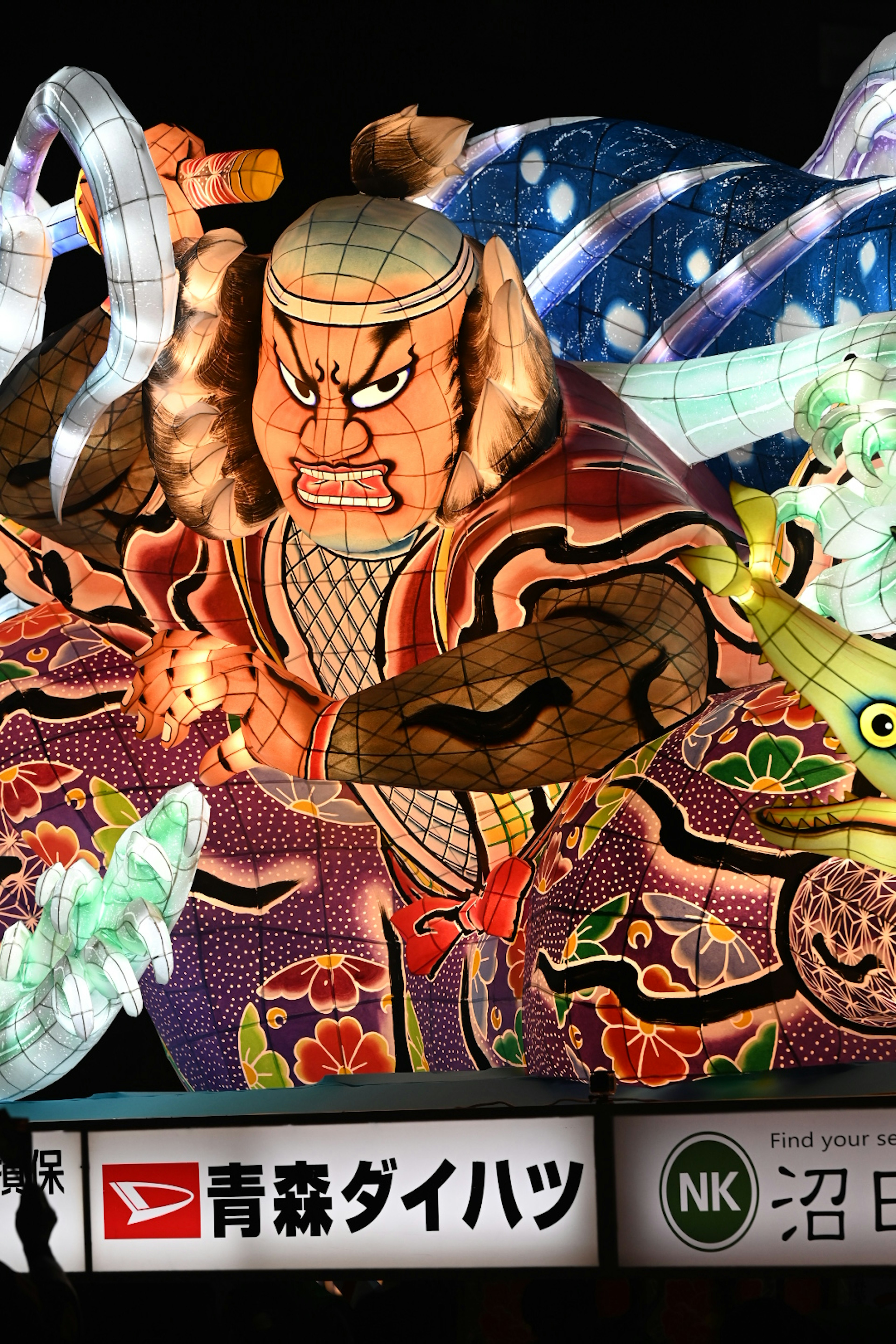 Gran figura iluminada del festival Nebuta de Aomori con colores vibrantes