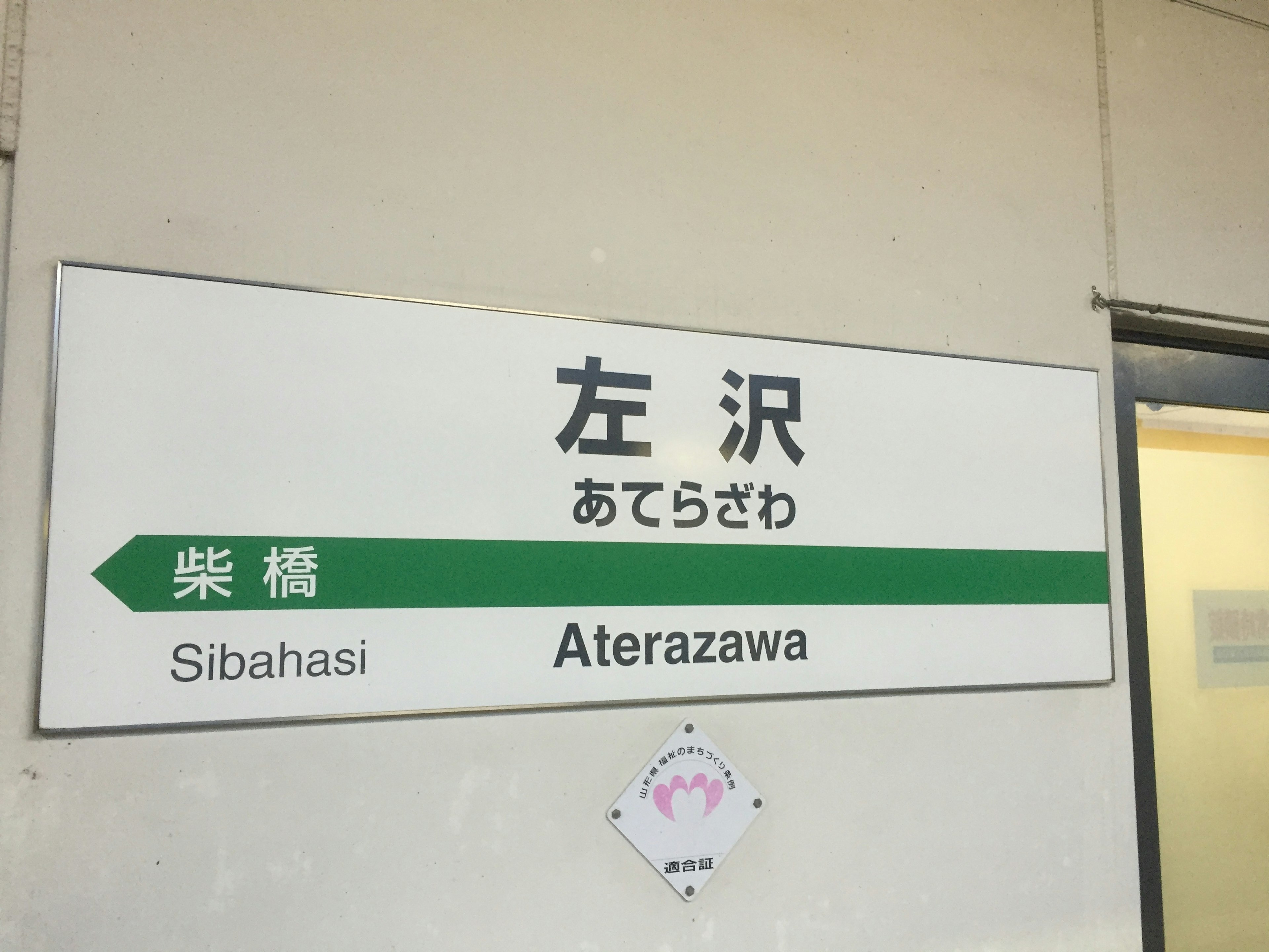 Schild der Aterazawa Station mit grünem Pfeil und Text