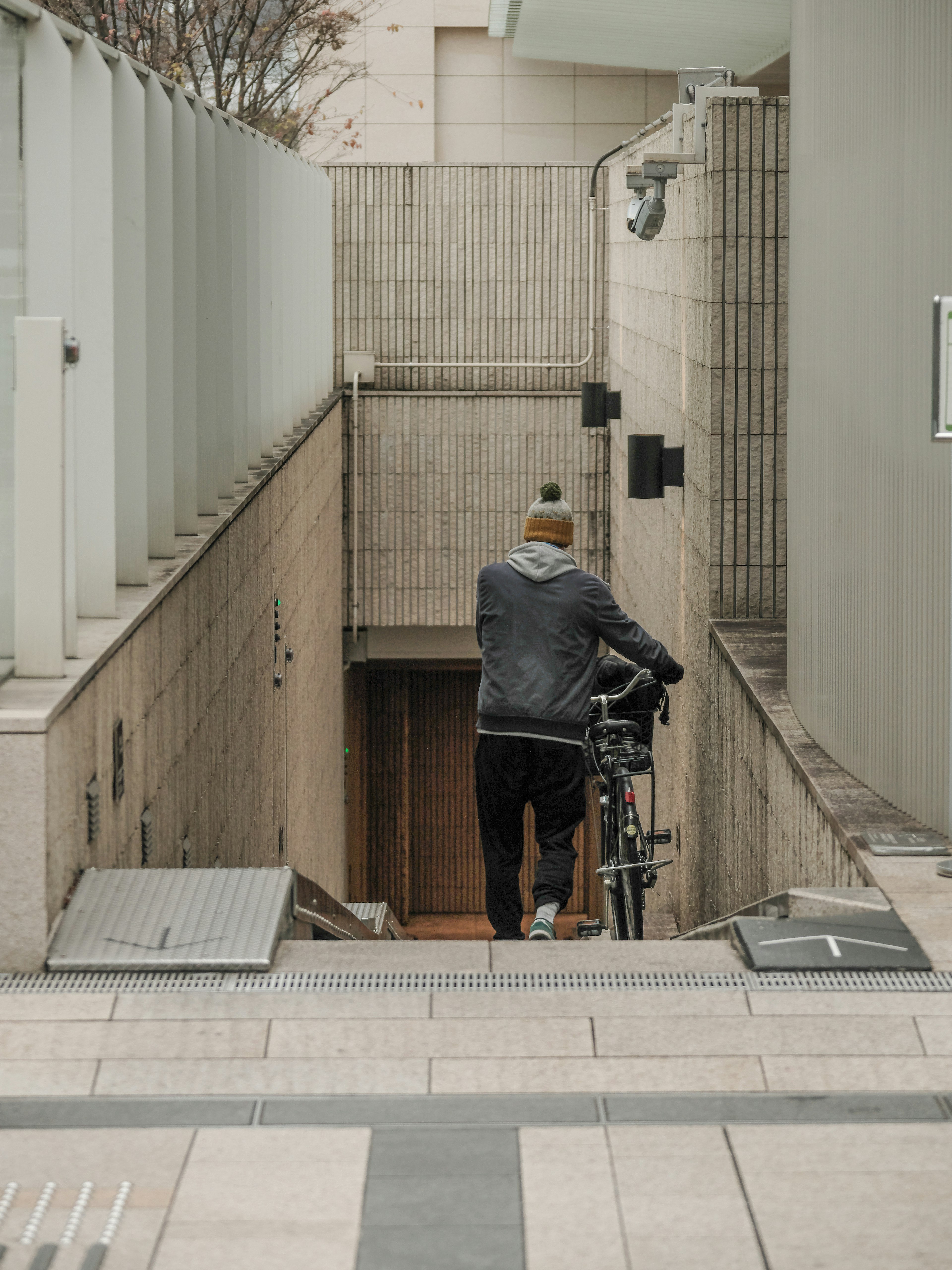 自転車を押しながら階段を下りる男性の後ろ姿