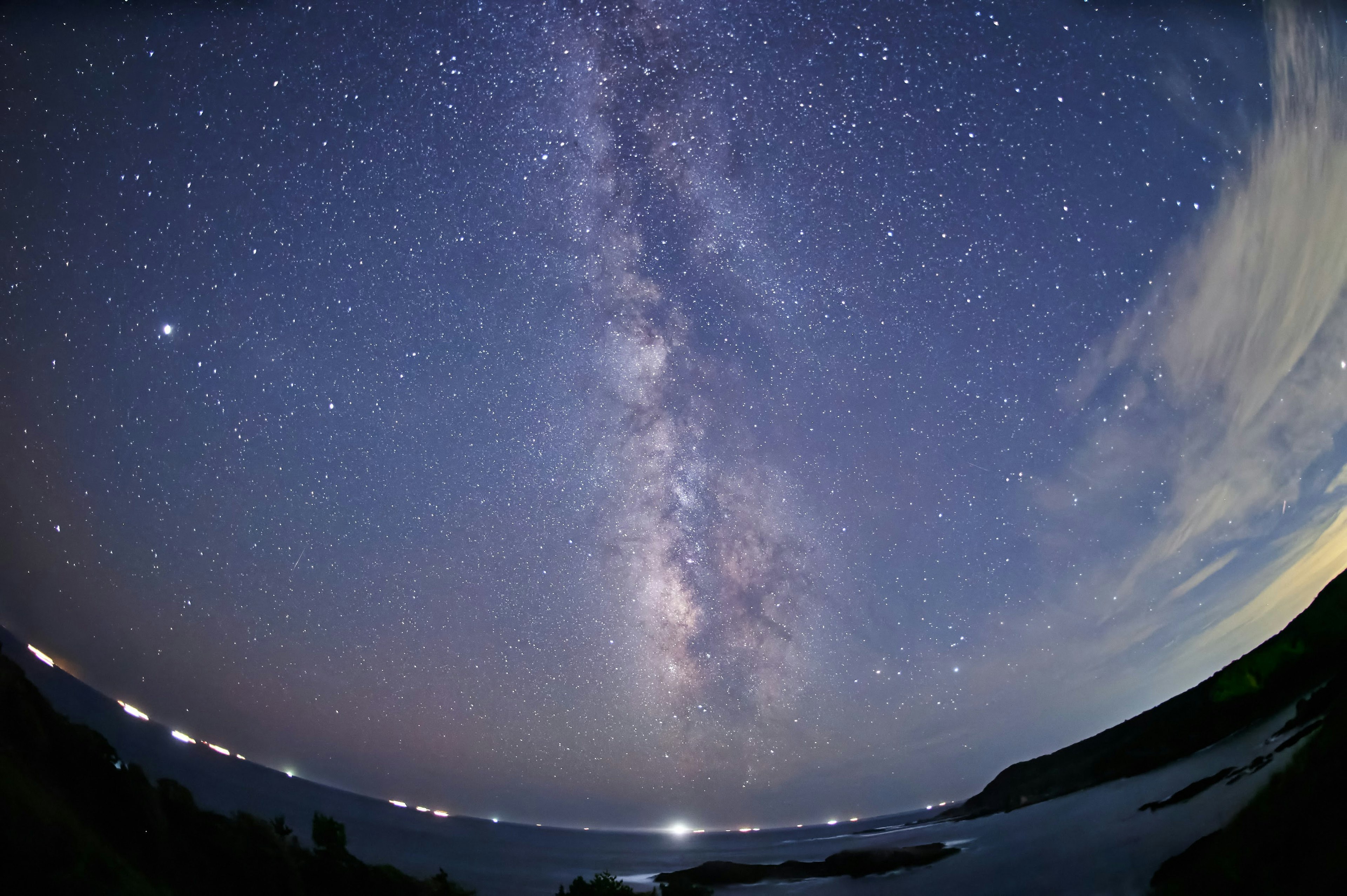 星空の下に広がる銀河系の美しい景色海と岸線が見える