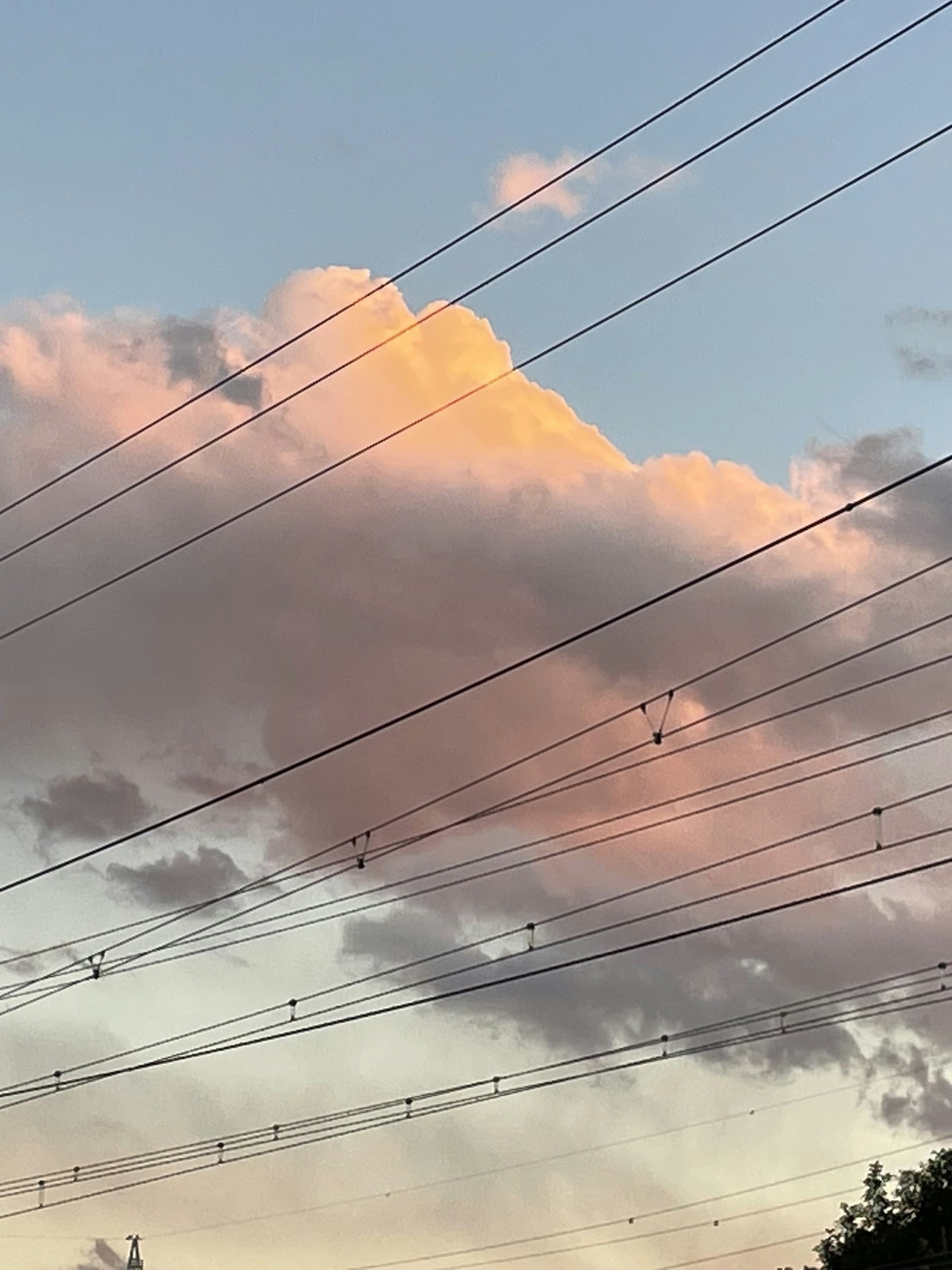 Awan saat matahari terbenam dengan kabel listrik di latar depan