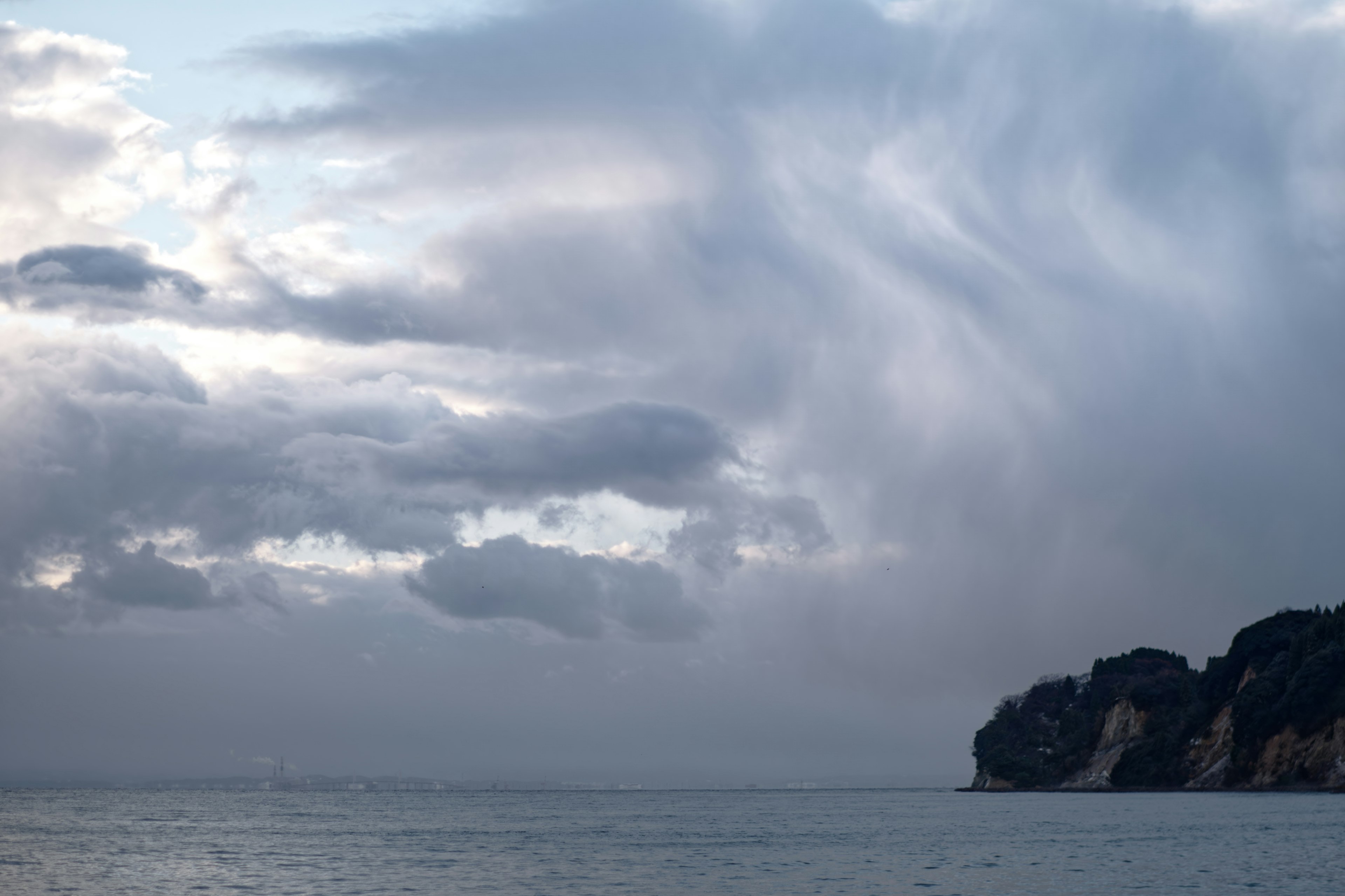 A beautiful landscape of sea and clouds featuring a rocky shoreline