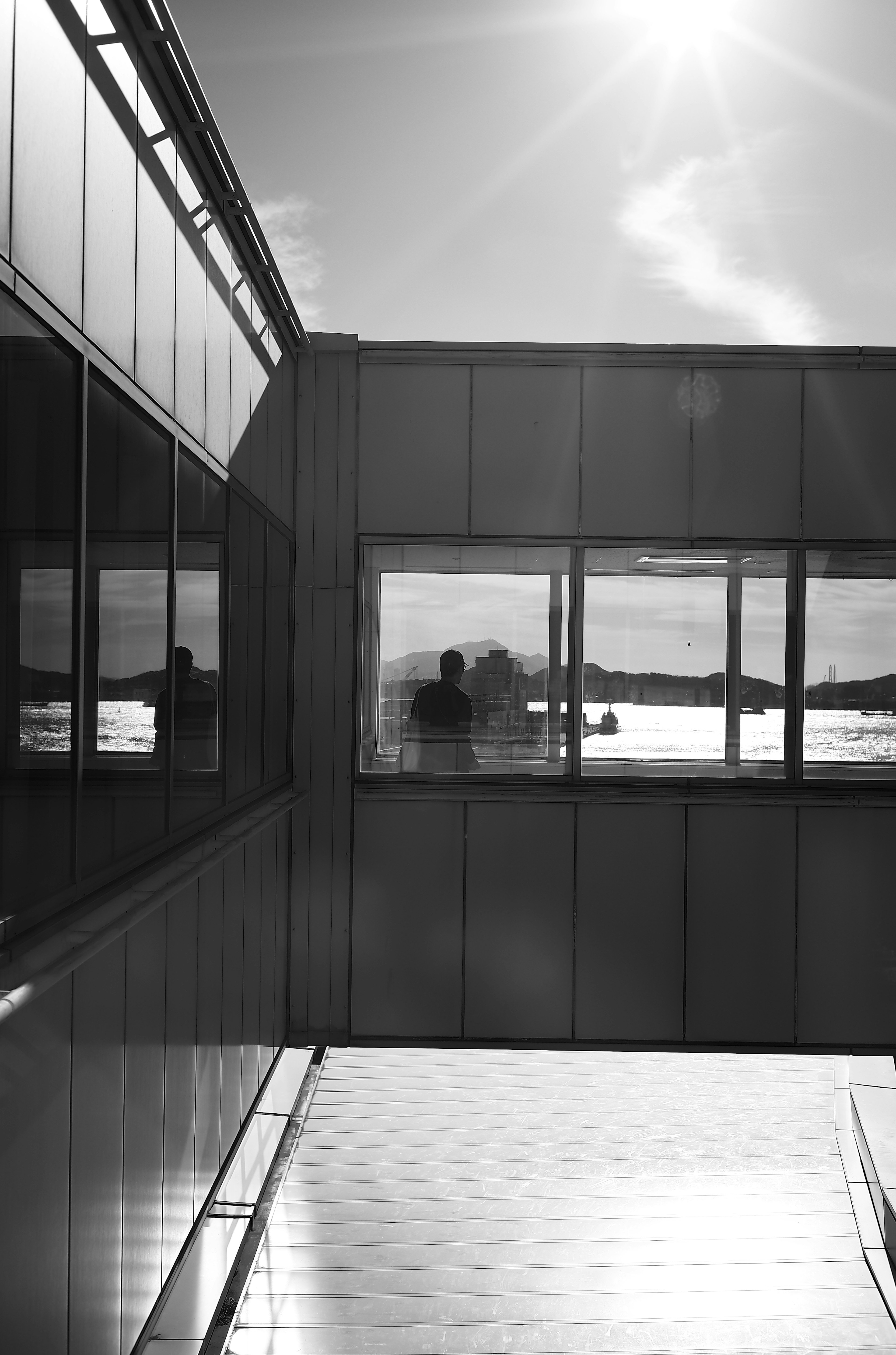 Silhouette of a person behind reflective windows of a modern building in black and white