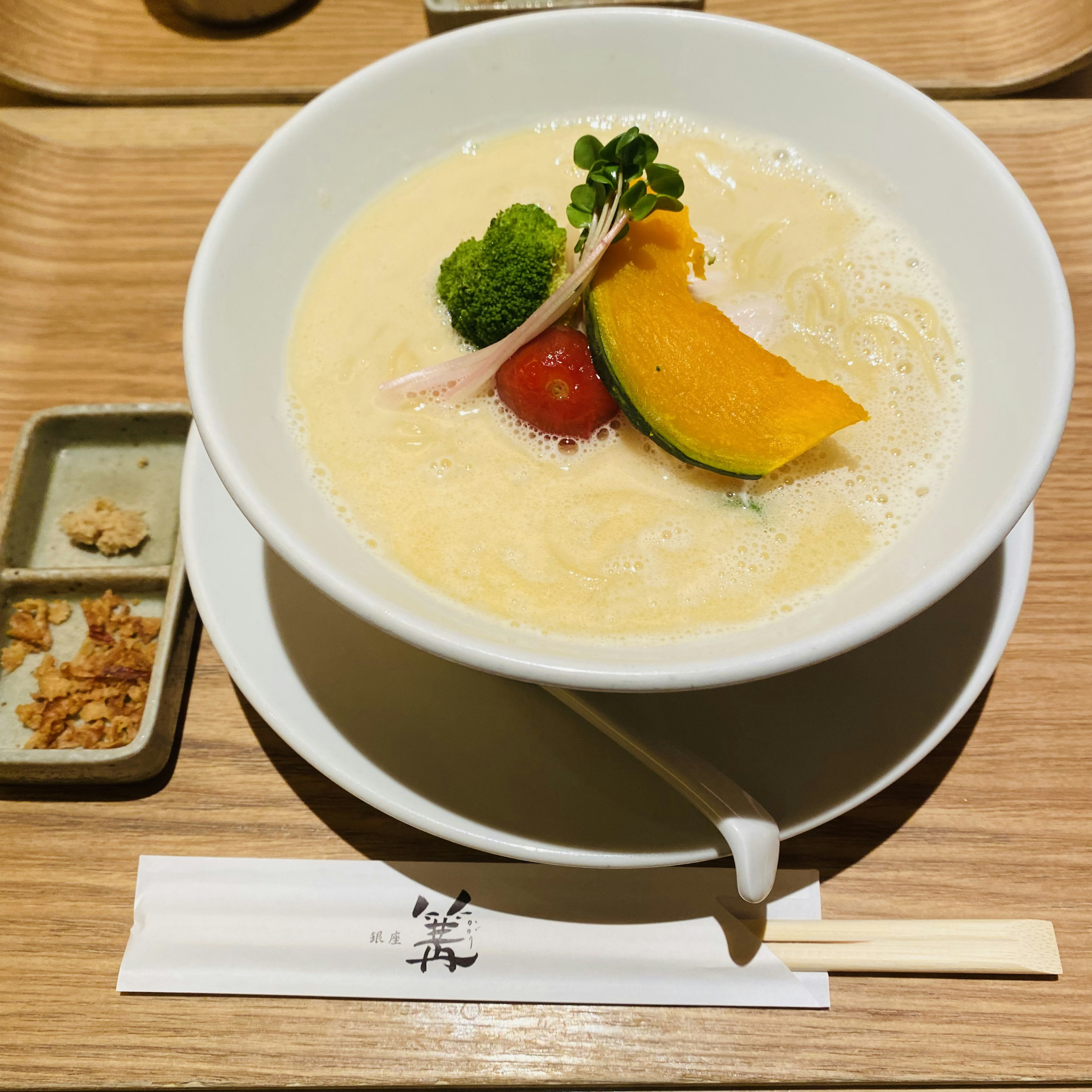 Cremige Suppe mit Brokkoli, Kirschtomaten und einem Stück Kürbis garniert