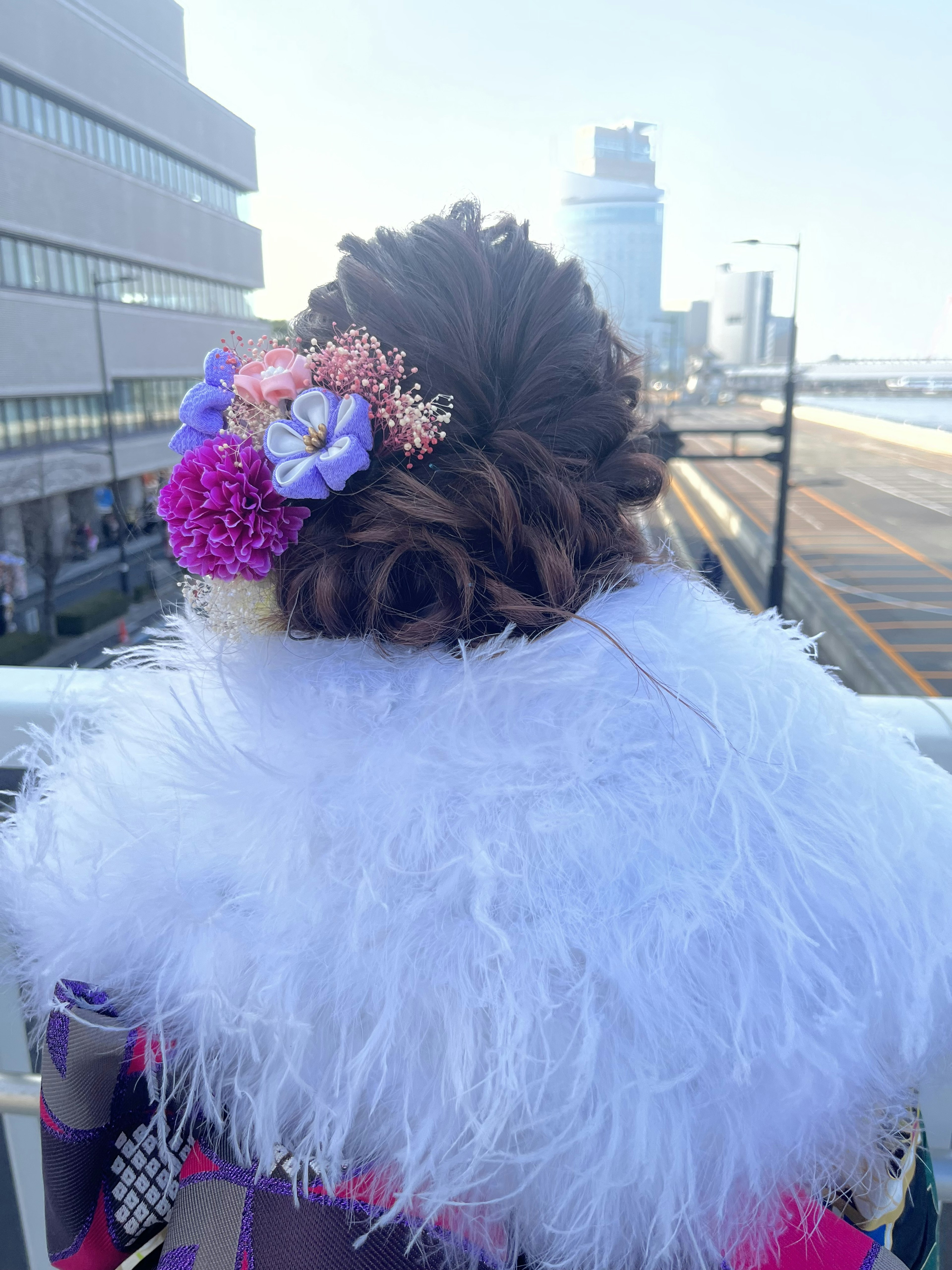 Back view of a woman with a colorful hair accessory and a white fur shawl