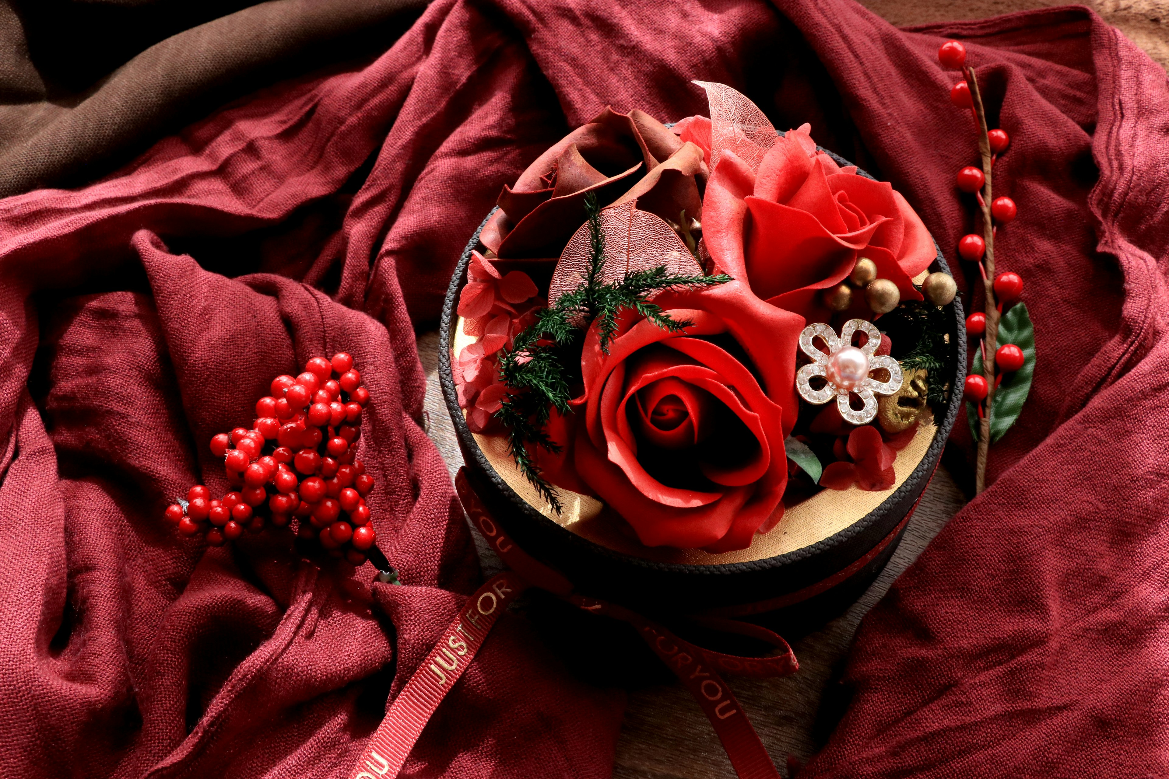 Arrangement floral avec des roses rouges et des éléments décoratifs sur un tissu rouge profond