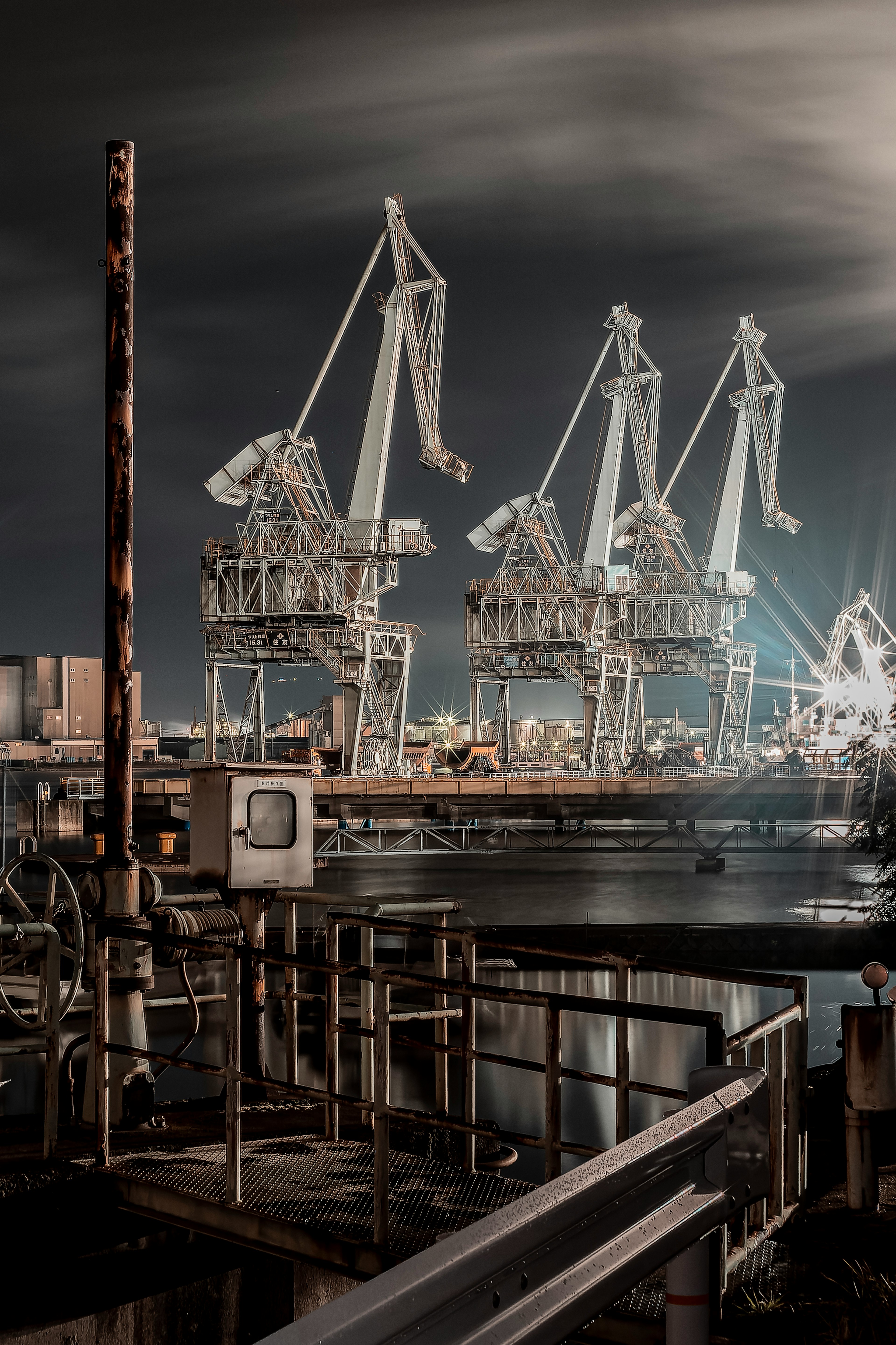 Industrial cranes standing in a nighttime port setting