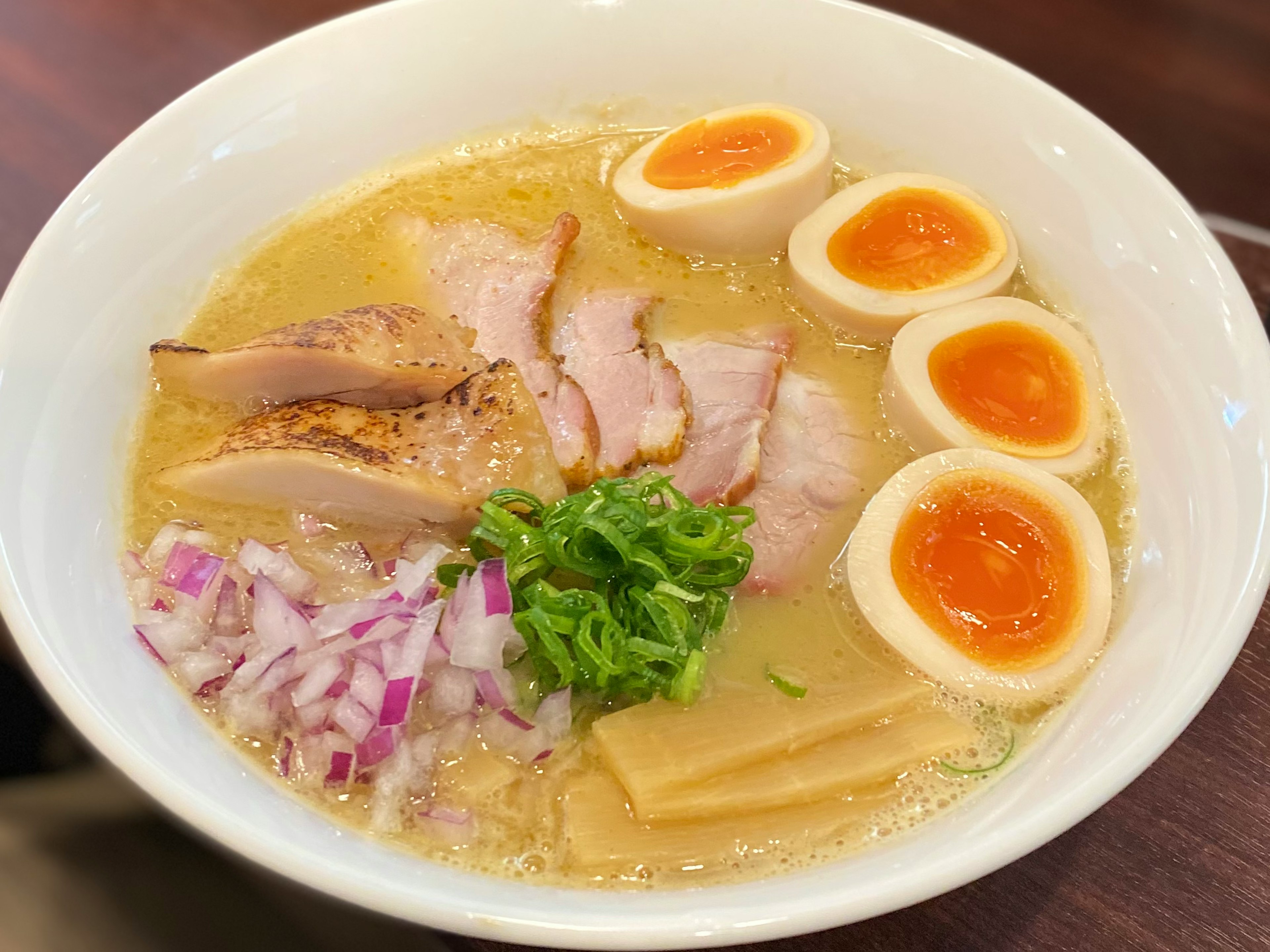 Mangkuk ramen yang lezat dengan irisan chashu, telur setengah matang, daun bawang, bawang ungu, dan menma