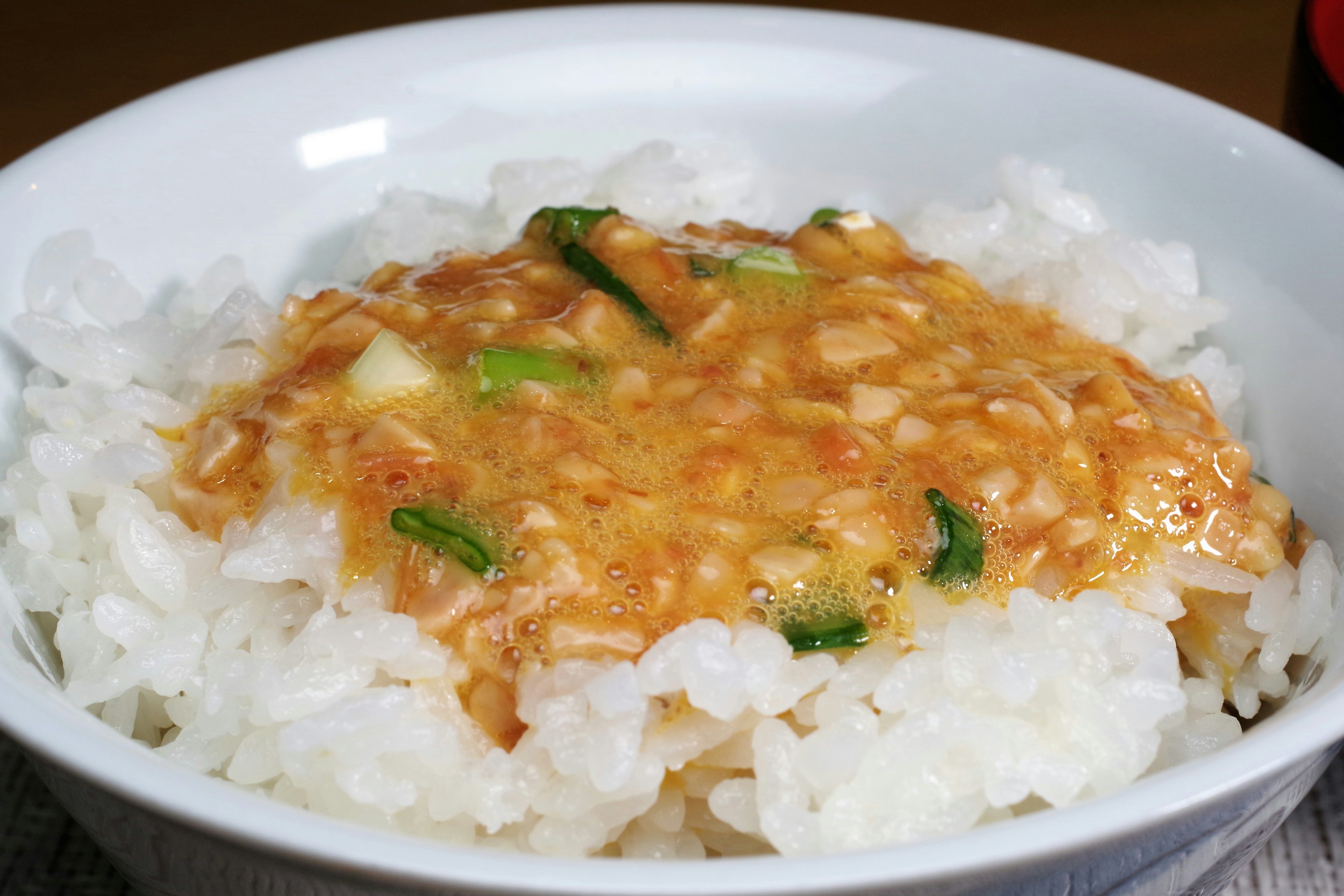 Mangkok nasi putih dengan saus telur dan bawang hijau