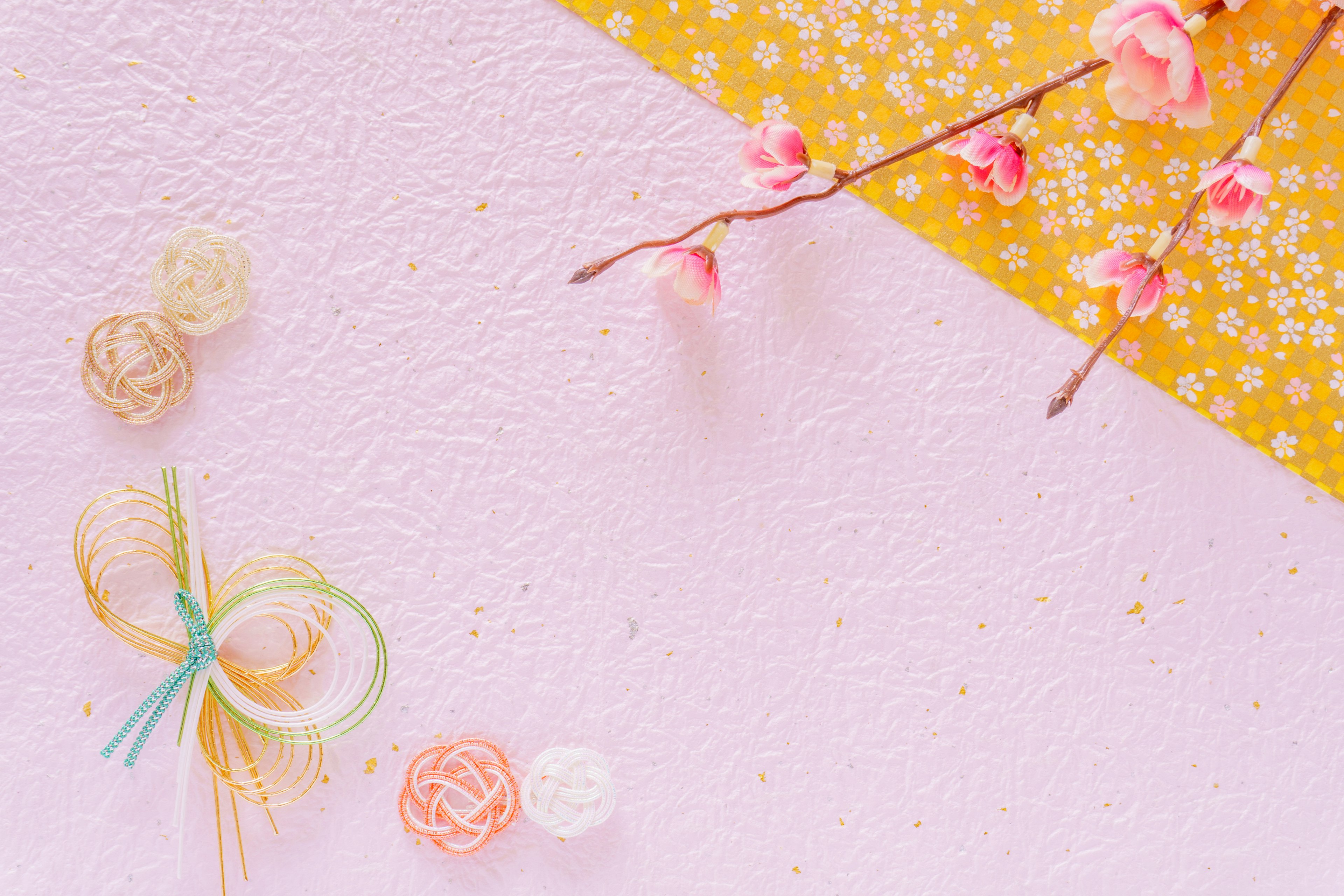 A pink background with a yellow patterned corner featuring cherry blossom branches and decorative flowers