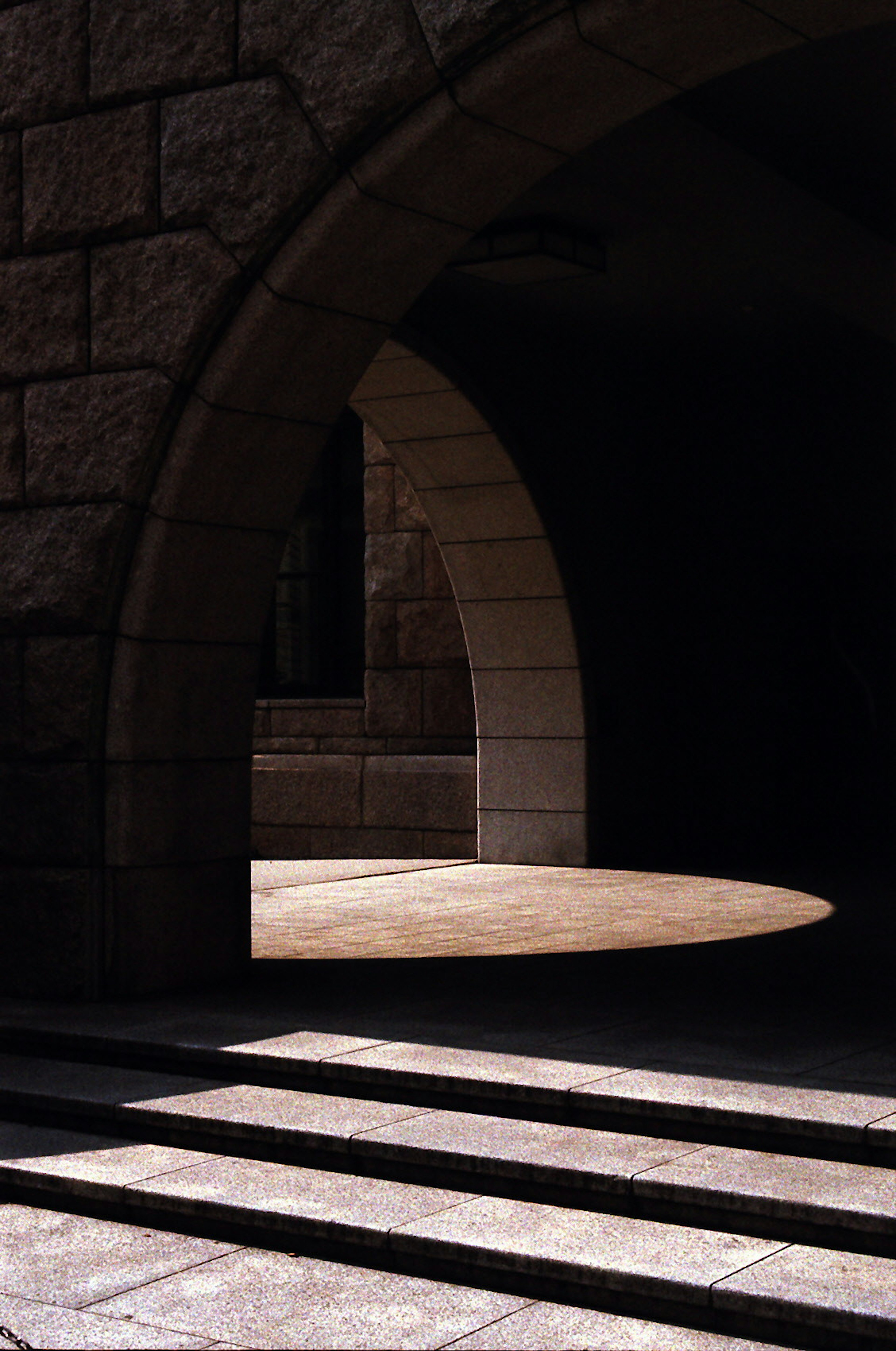 Beautiful contrast of light and shadow through an arched entrance of a stone building