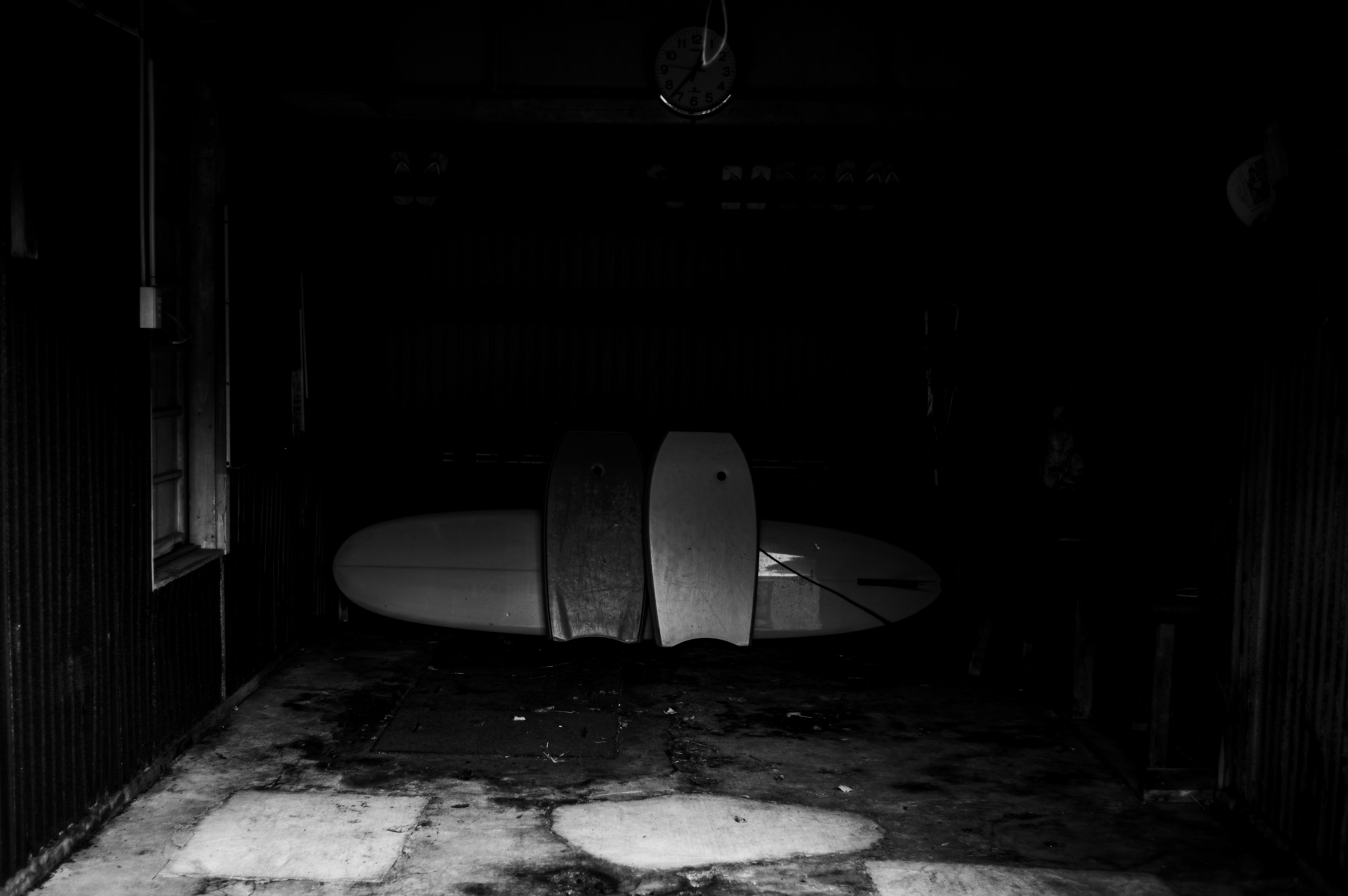 Three surfboards positioned in a dark garage setting