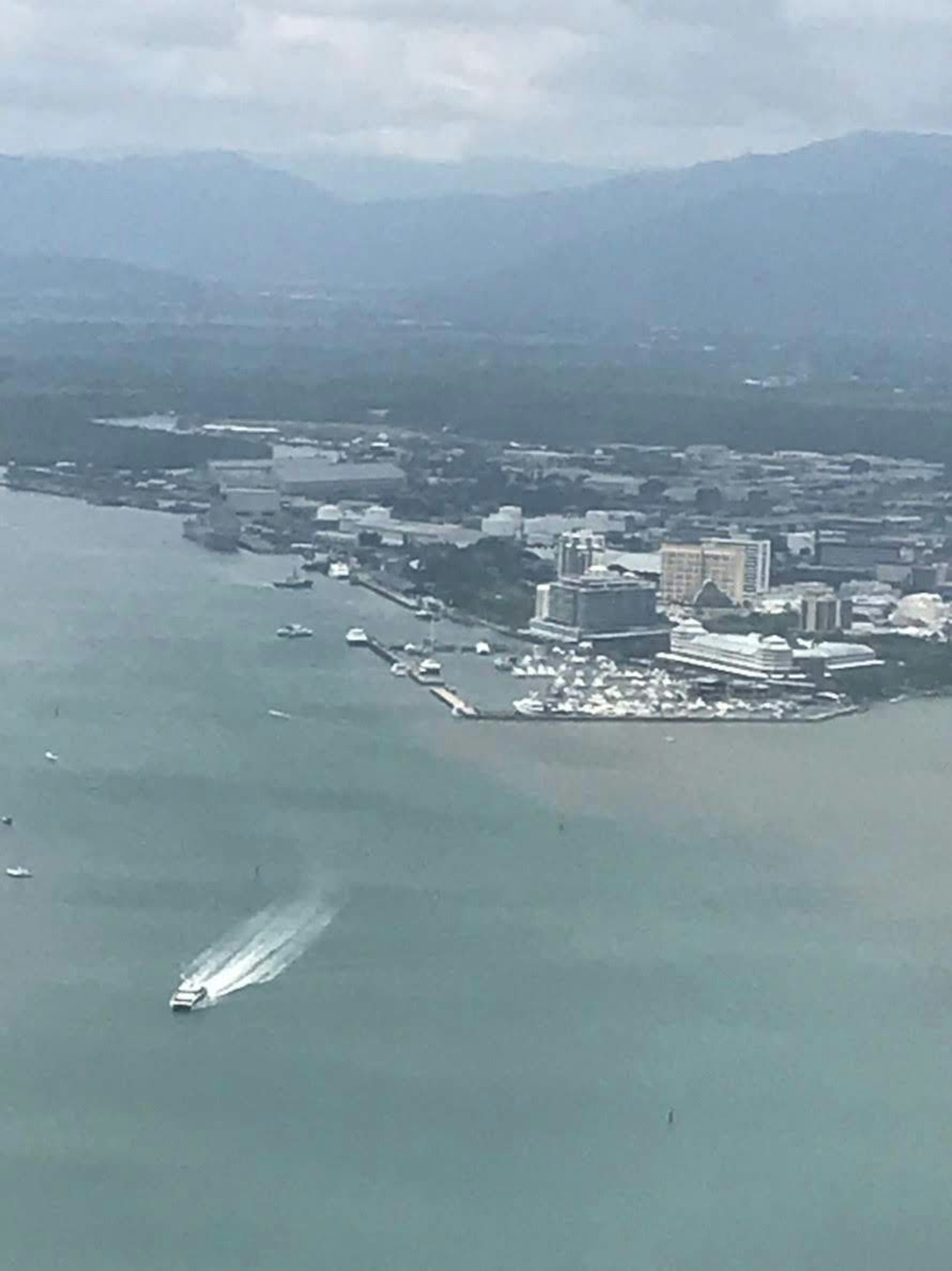 Aerial view of a coastal city with boats and mountains in the background