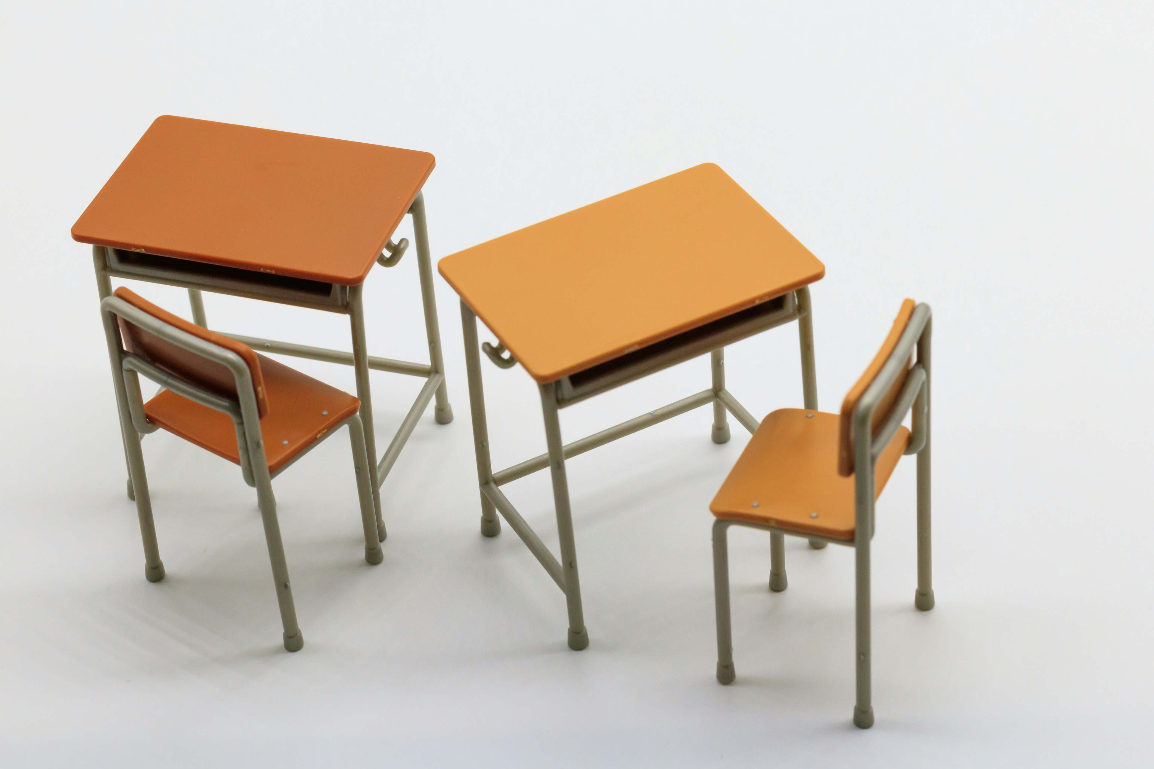 Three orange desks and chairs arranged creatively