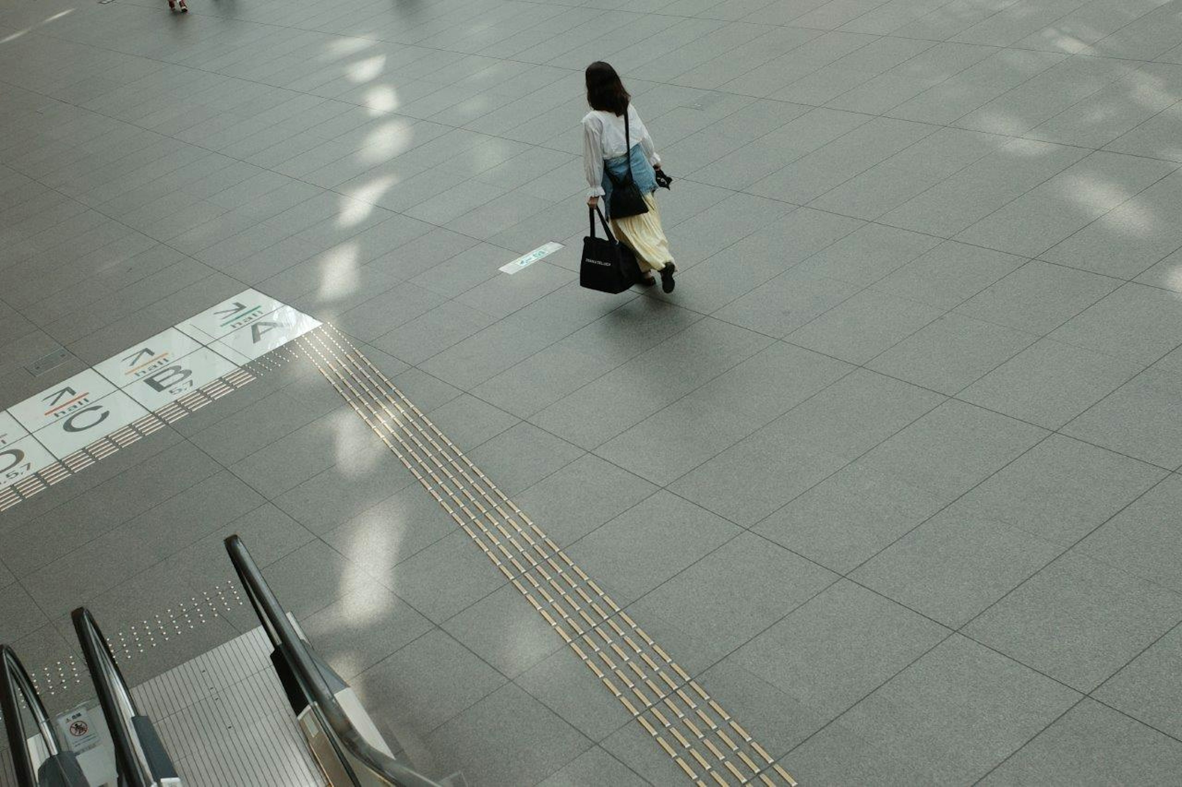 駅の広場でバッグを持った女性が歩いている光景