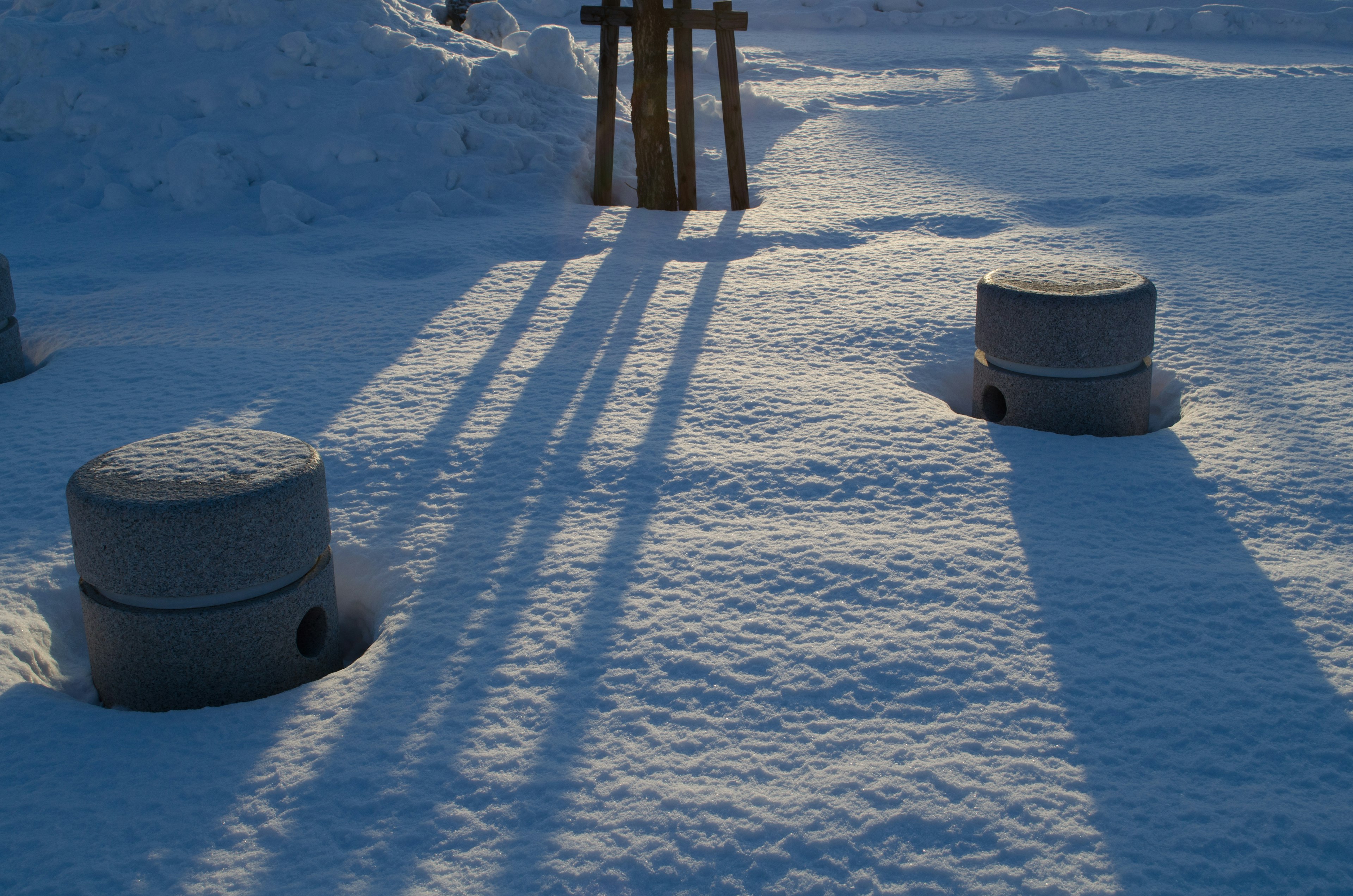 Landschaft mit zwei kreisförmigen Strukturen auf schneebedecktem Boden und langen Schatten