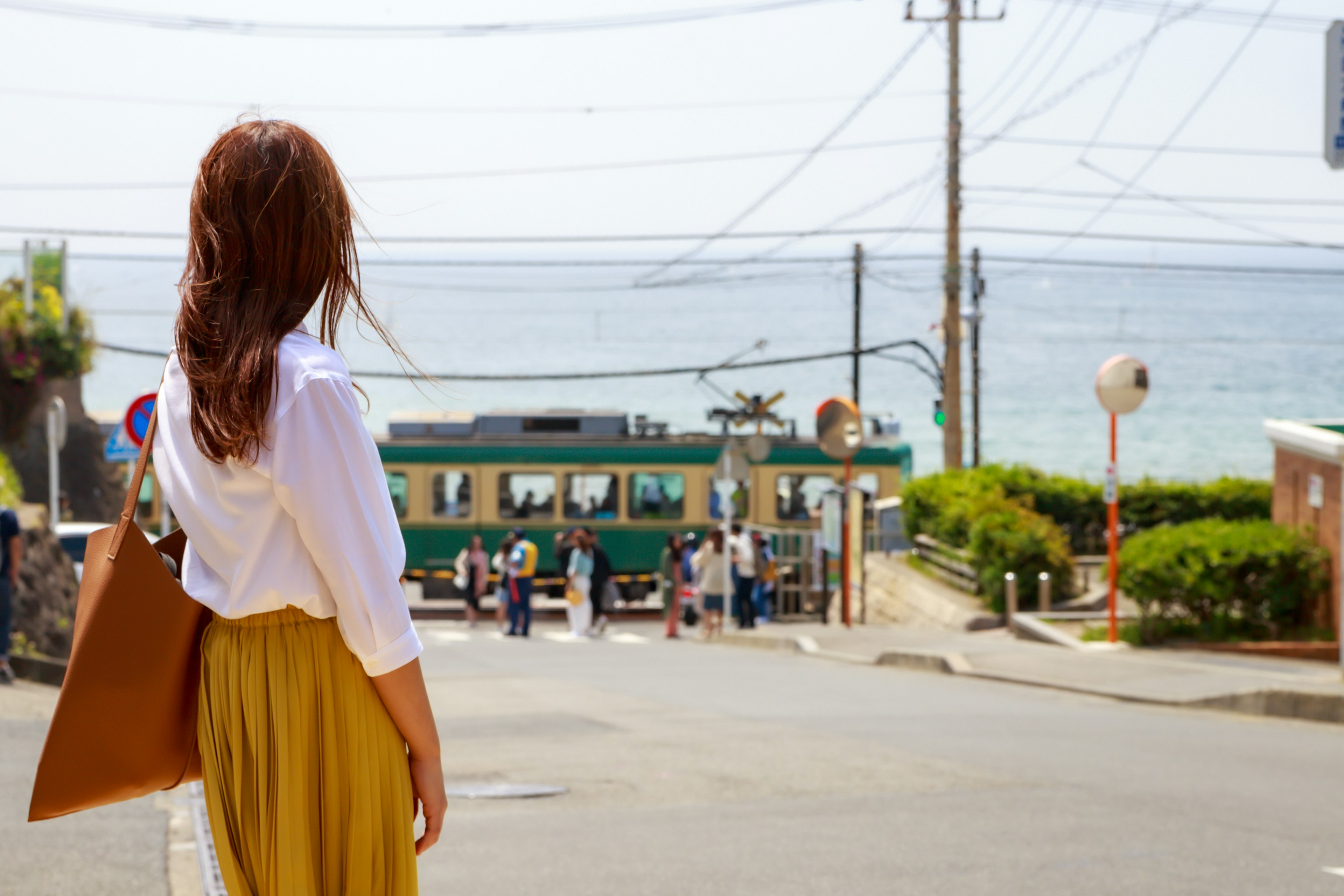 Frau, die auf das Meer schaut, mit einer Straßenbahn im Hintergrund