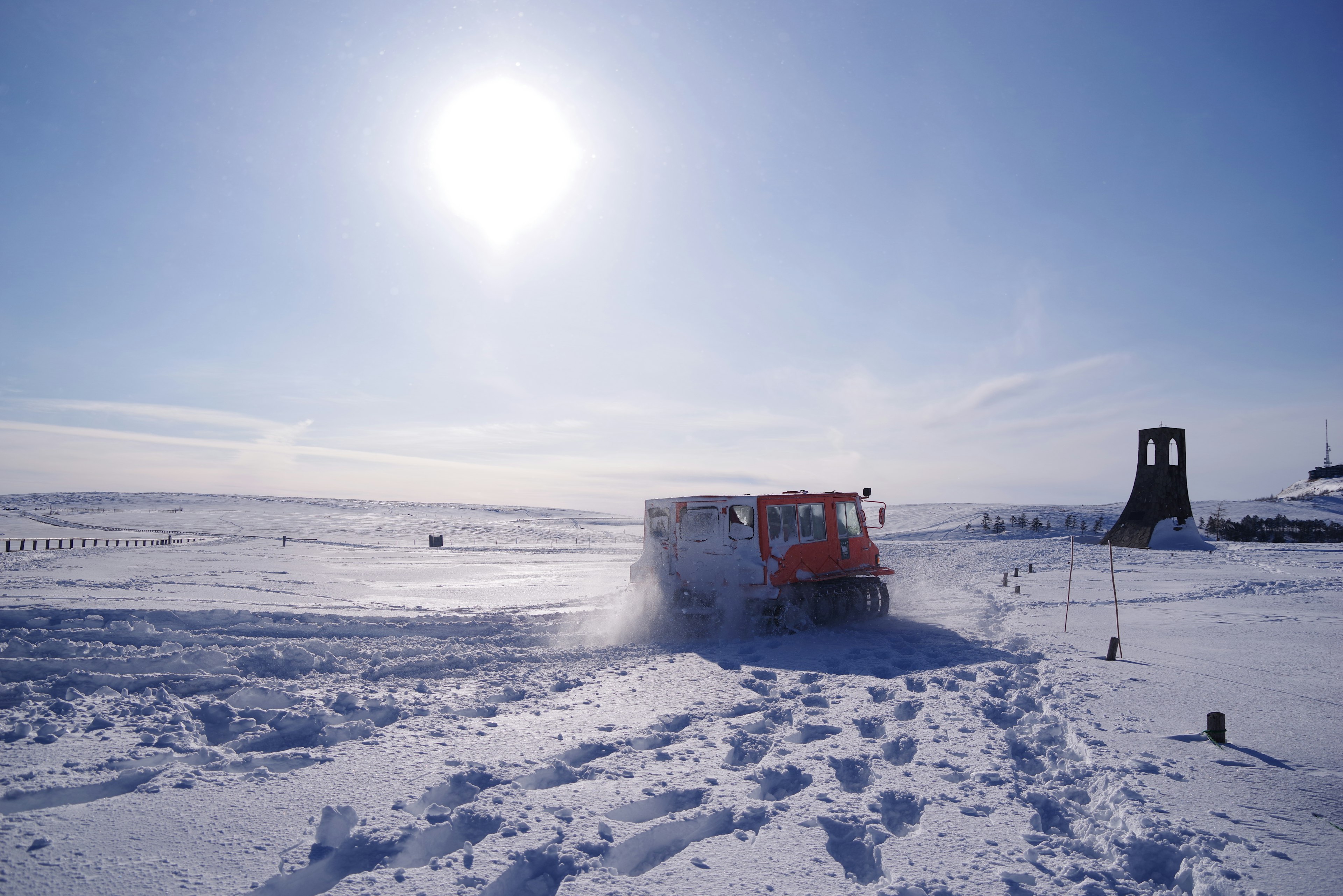 Red snowplow on a snowy landscape with a bright sun