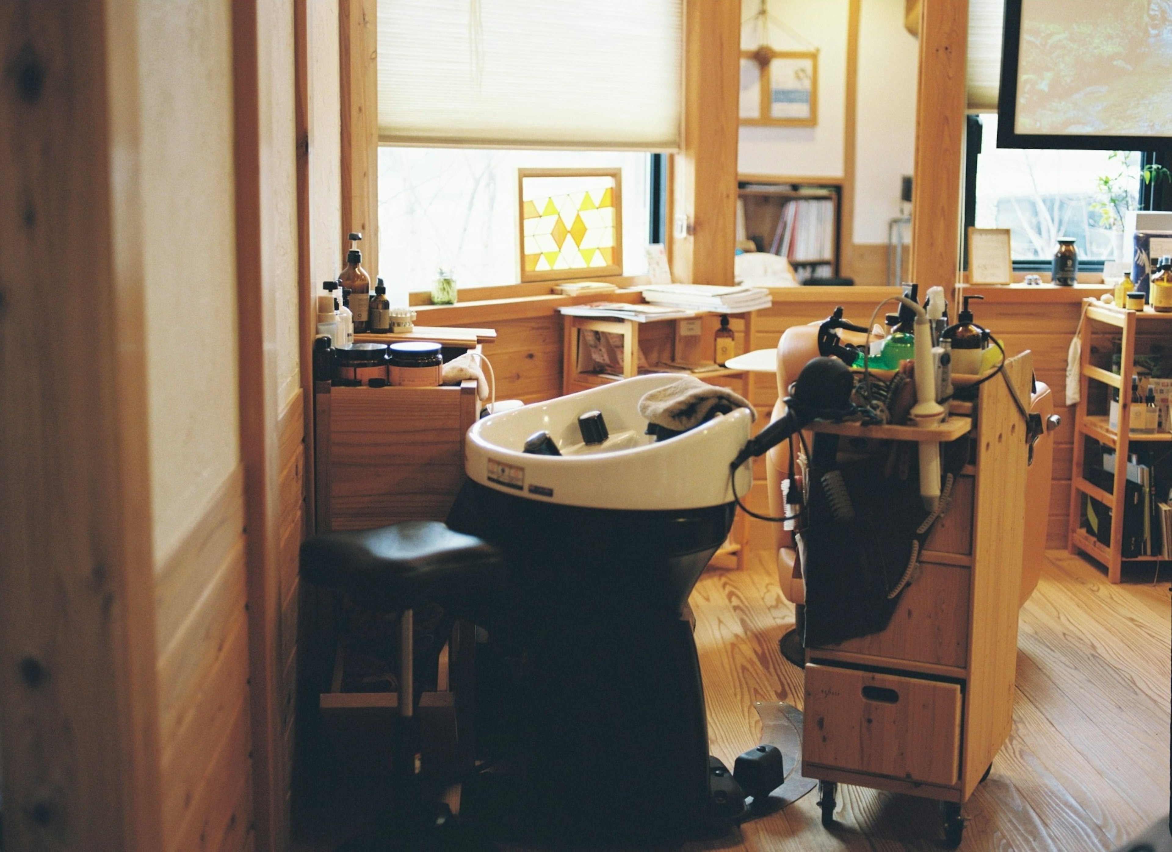 Interior of a hair salon featuring a shampoo station and wooden furniture