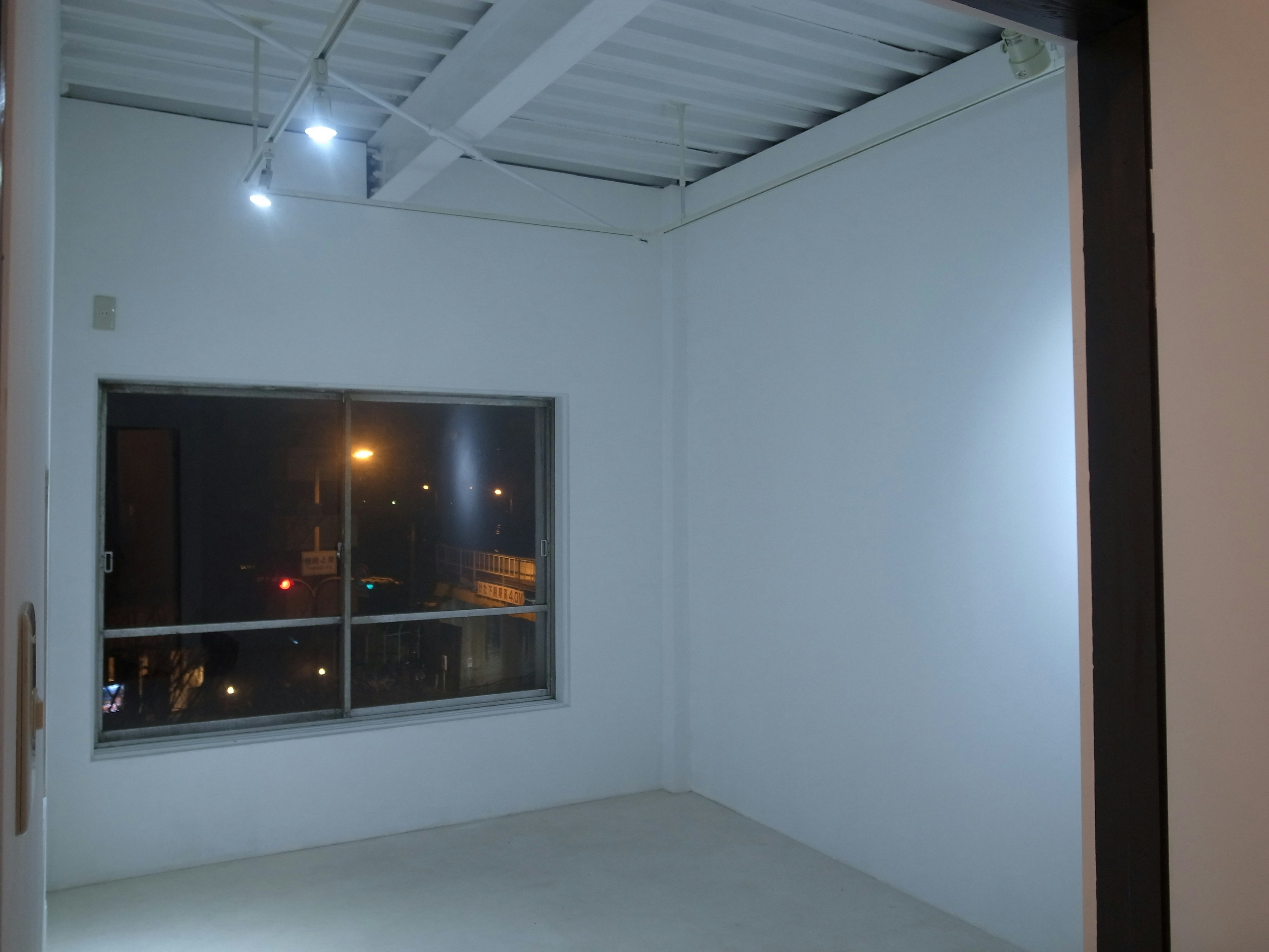 Empty room with white walls featuring a window showing city lights