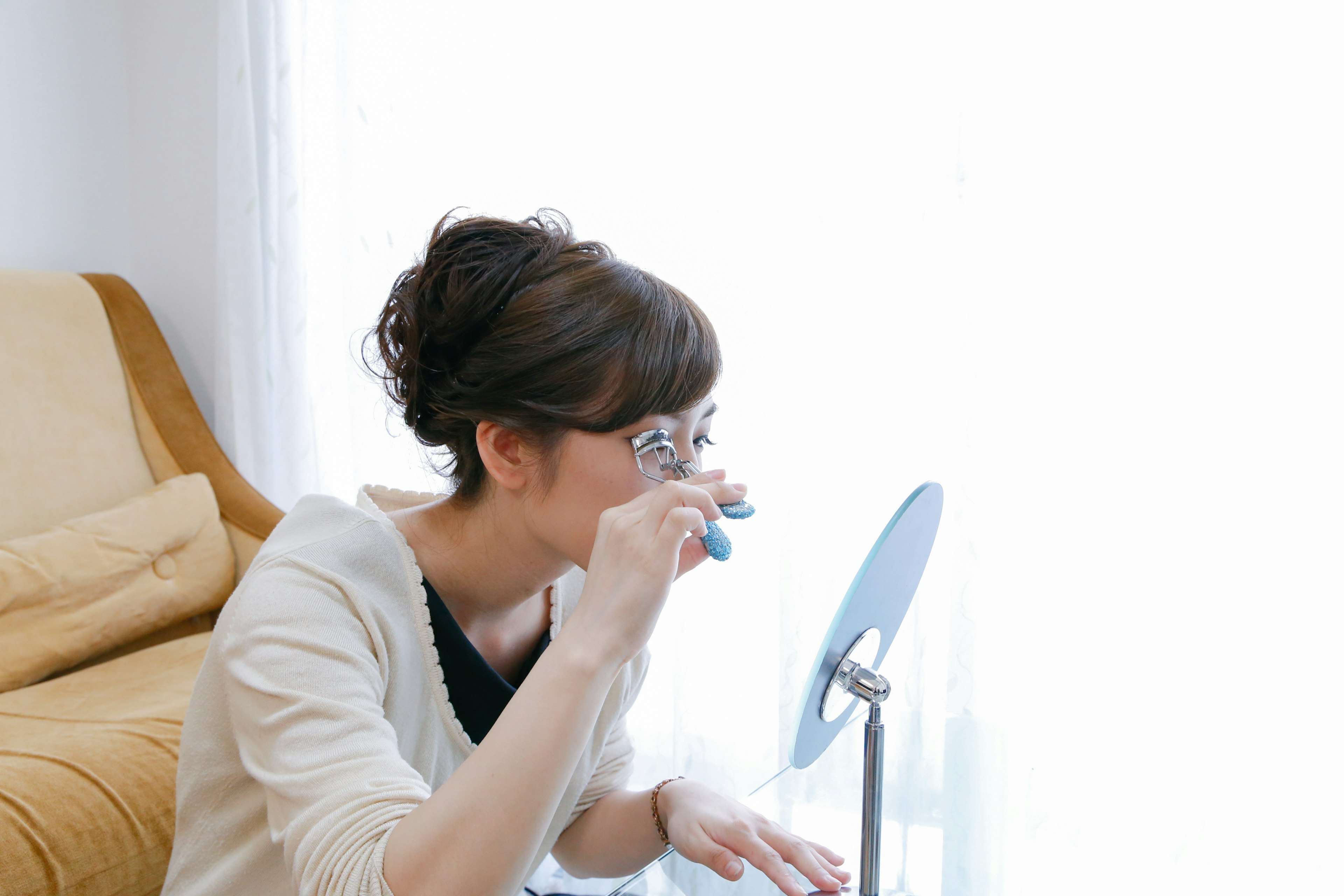 A woman examining something in a mirror in a bright room with natural light