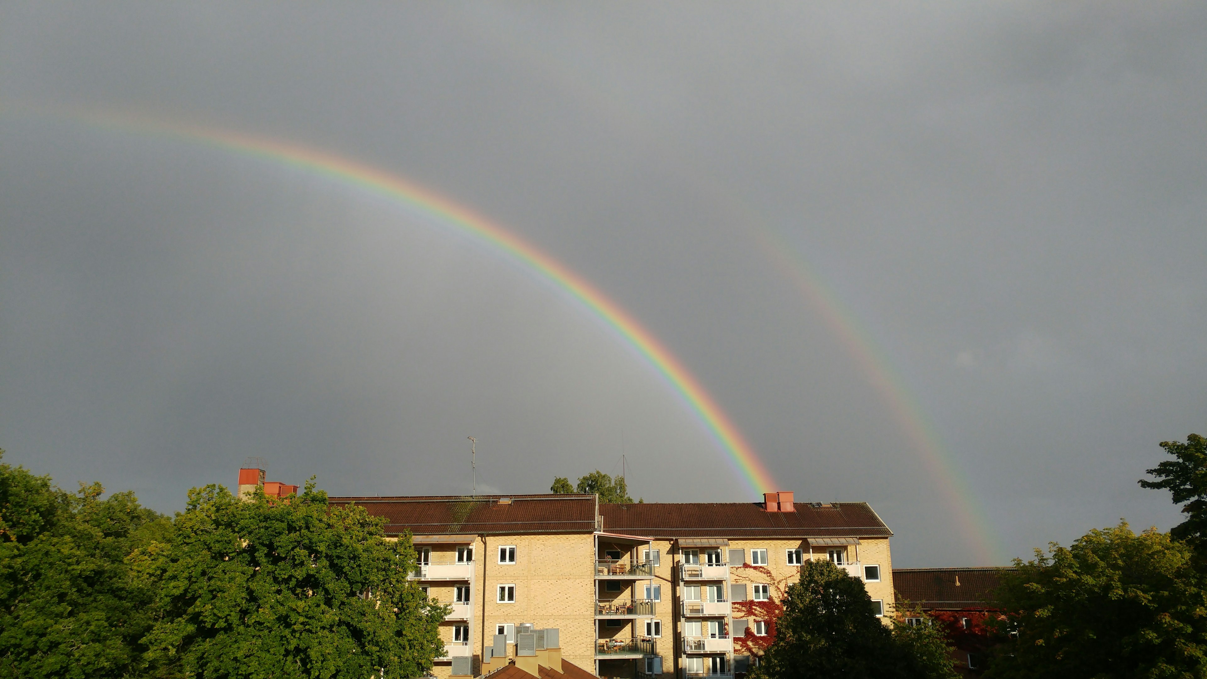 Doble arco iris sobre edificios residenciales después de la lluvia