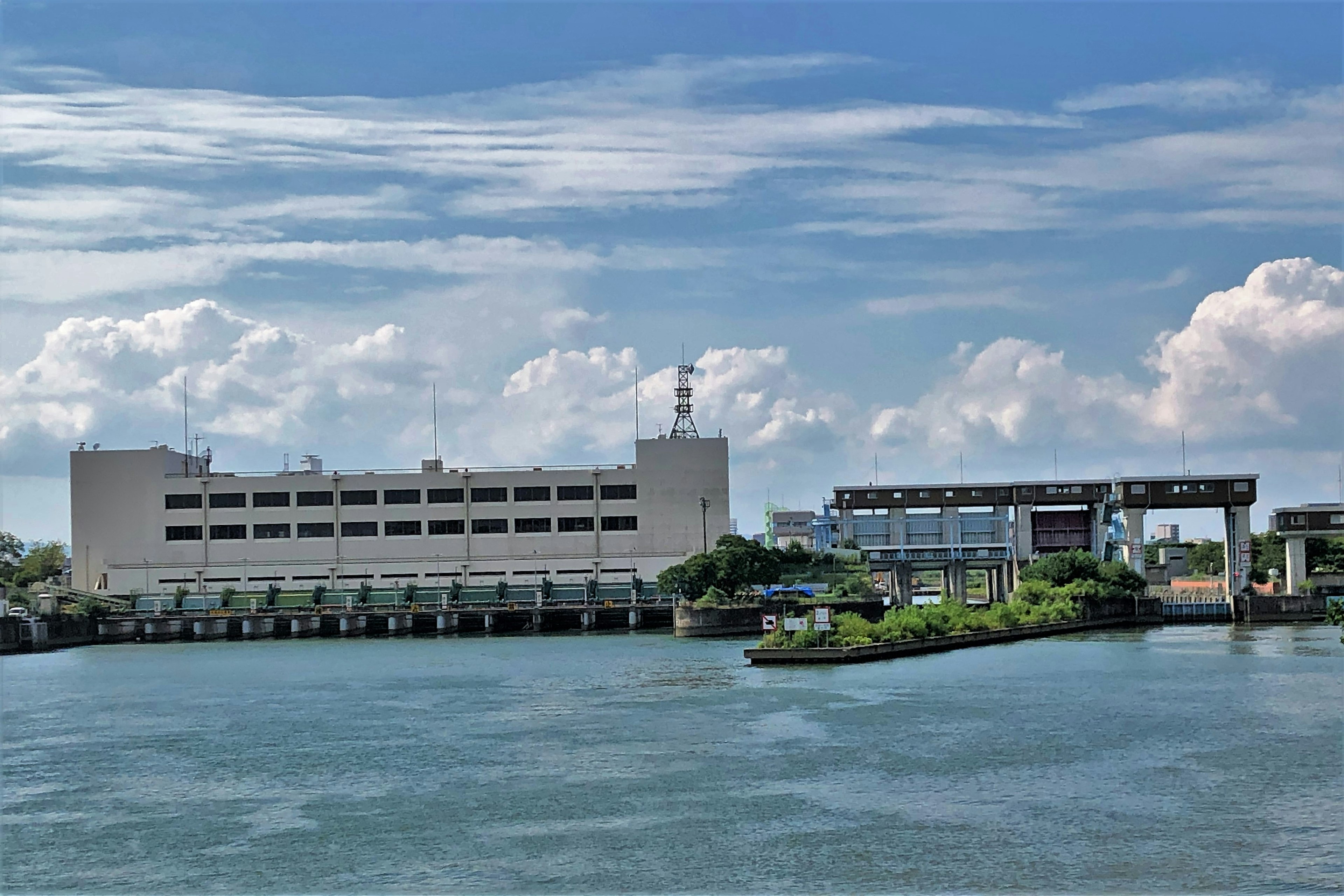 Una vista del río con un edificio y un puente bajo un cielo azul y nubes blancas