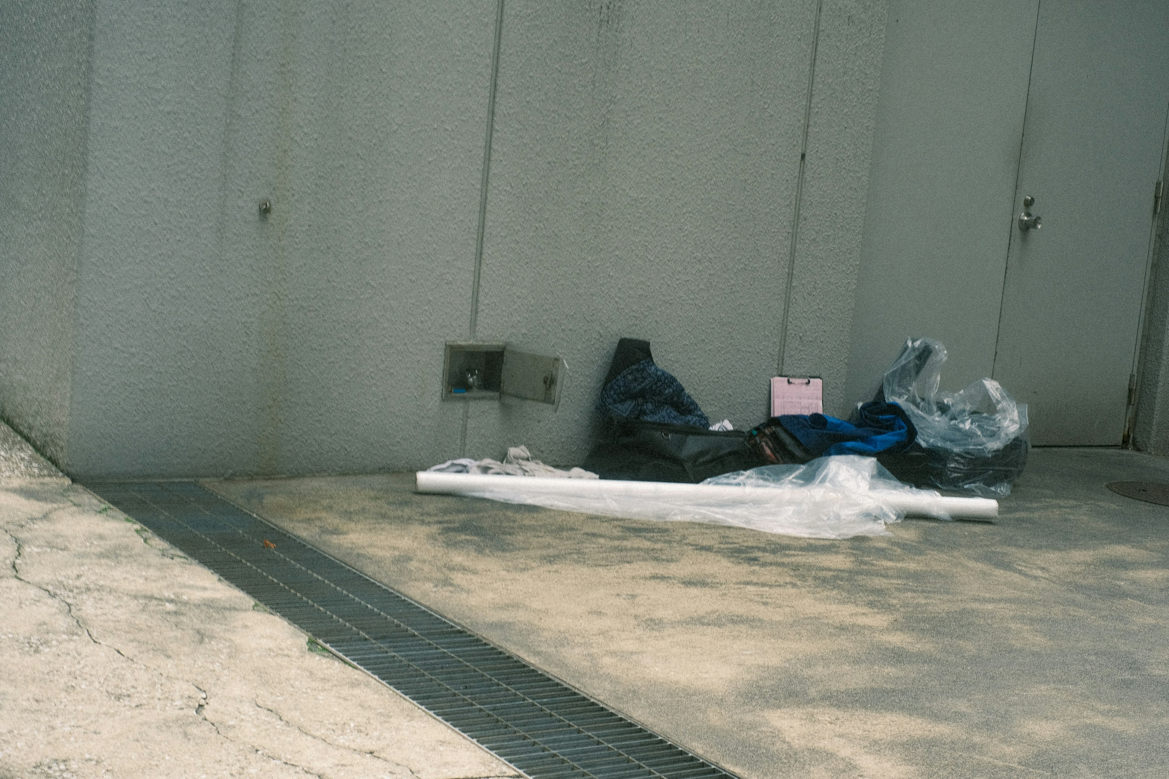 A pile of trash bags and plastic near a wall