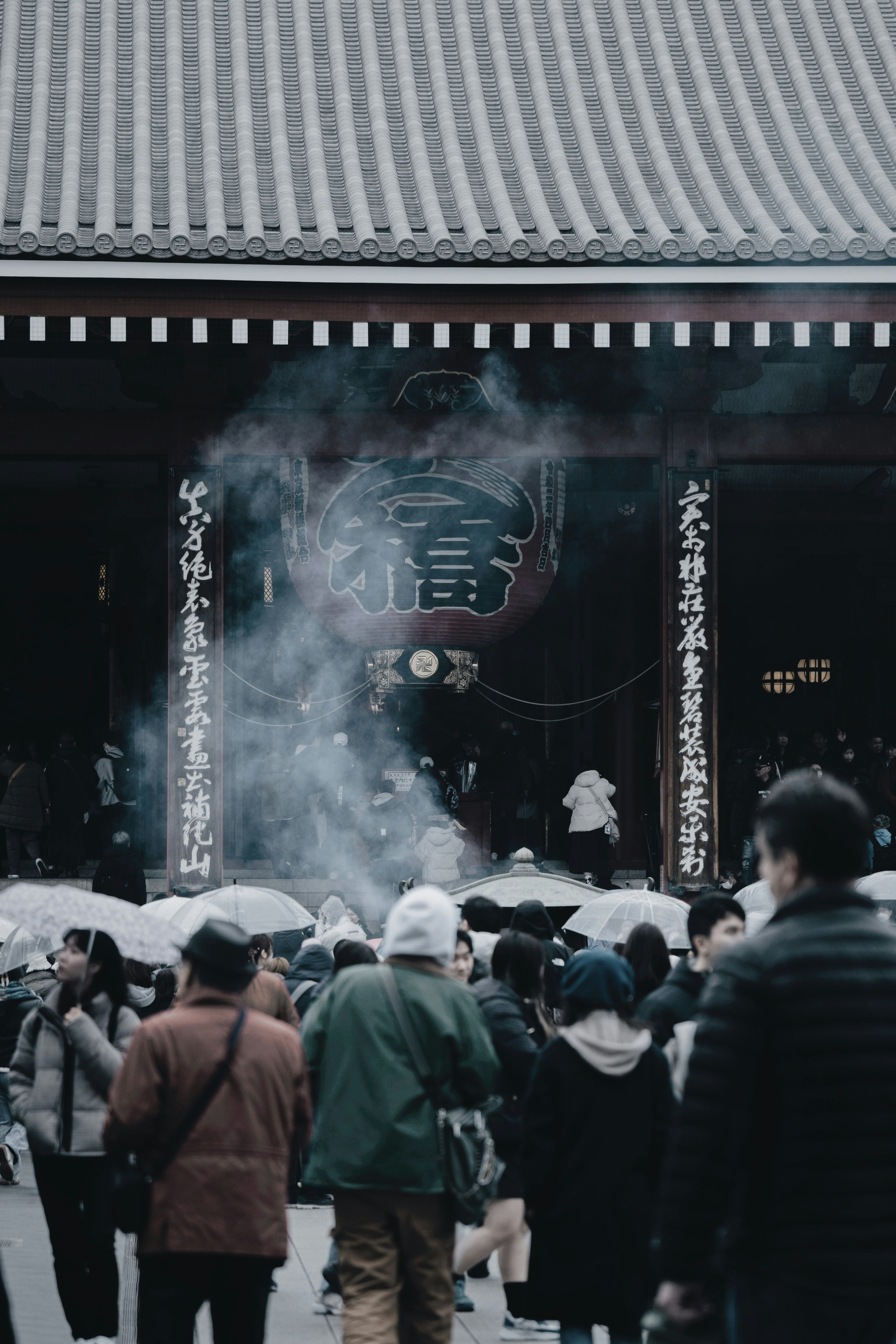 人々が煙を浴びながら寺の入り口に集まっているシーン