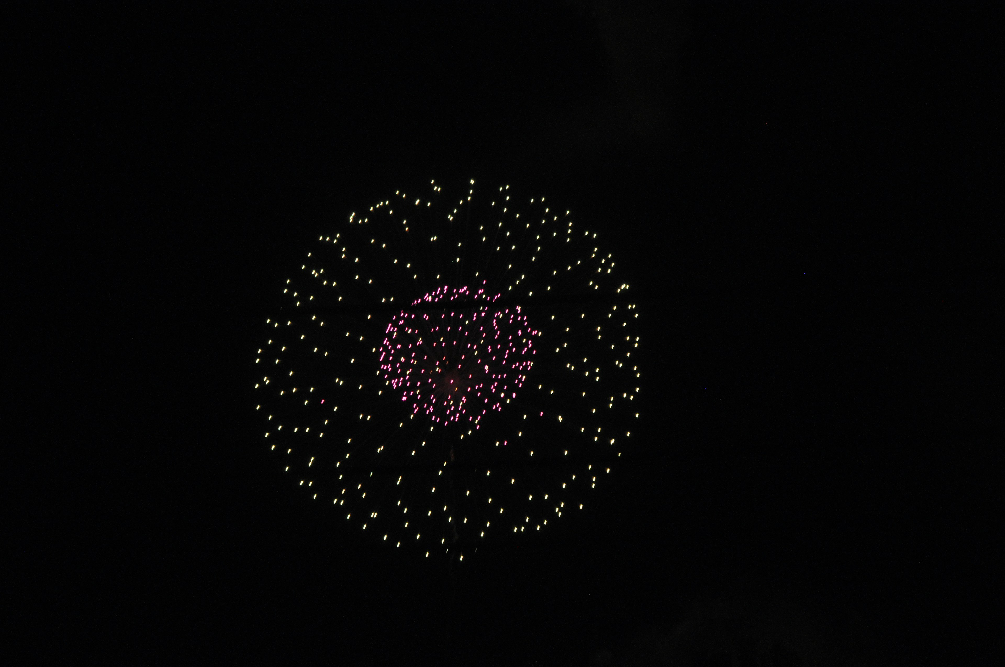 Un affichage de feux d'artifice colorés sur fond noir avec un cercle rose central