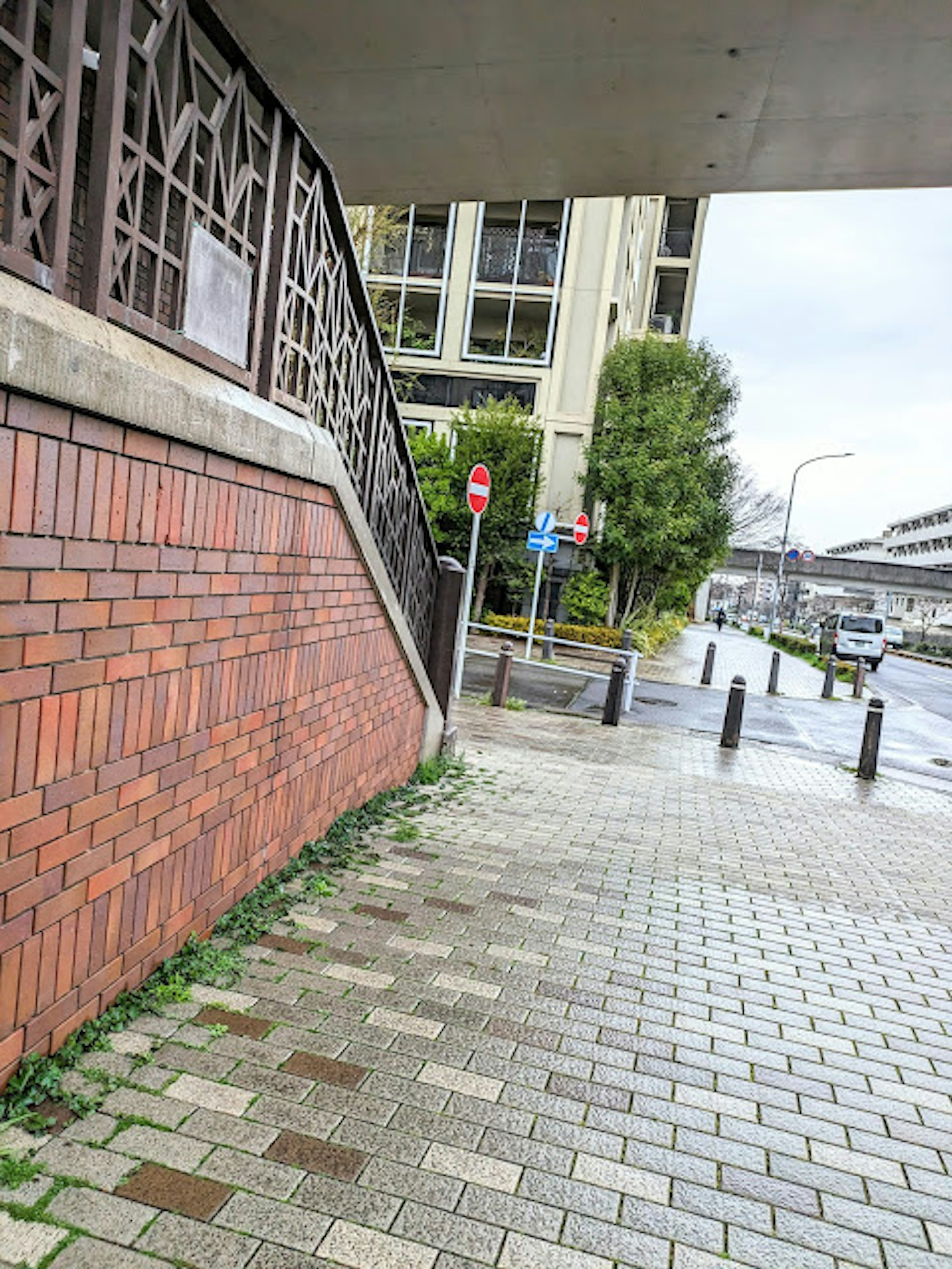 Vista di un muro di mattoni e un marciapiede pavimentato con un edificio sullo sfondo