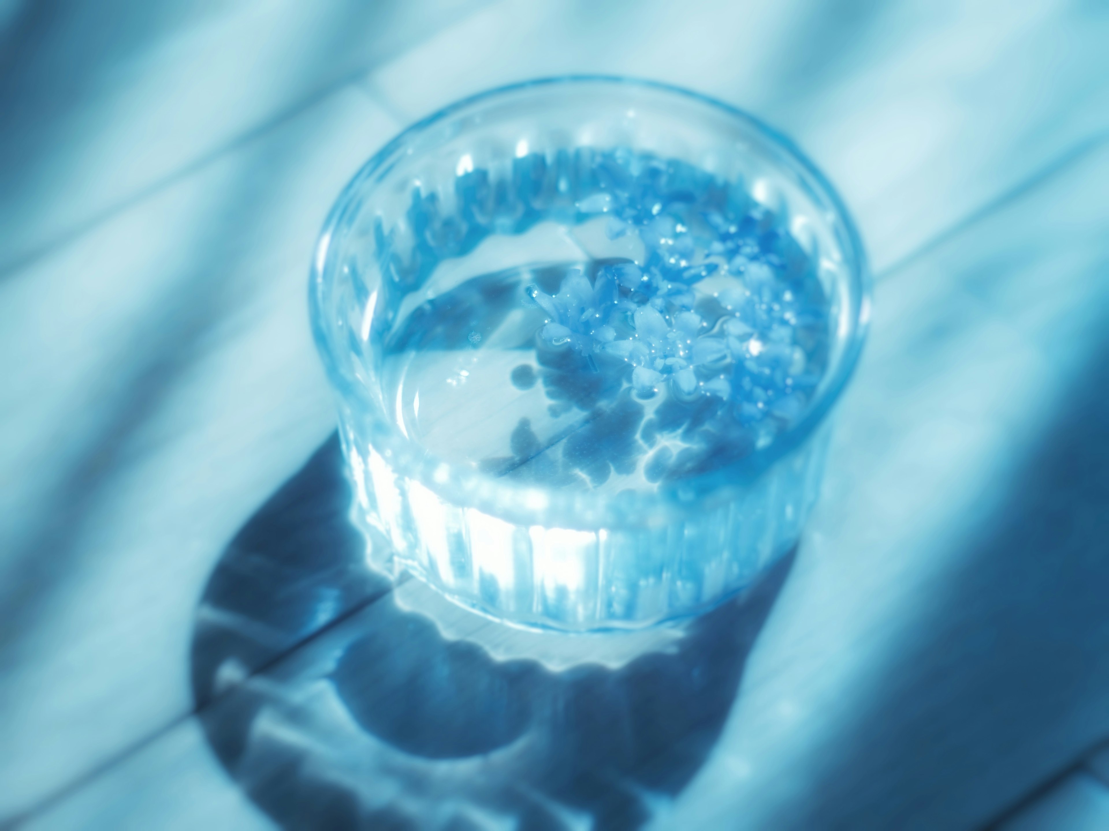 A clear glass bowl filled with blue water placed on a table