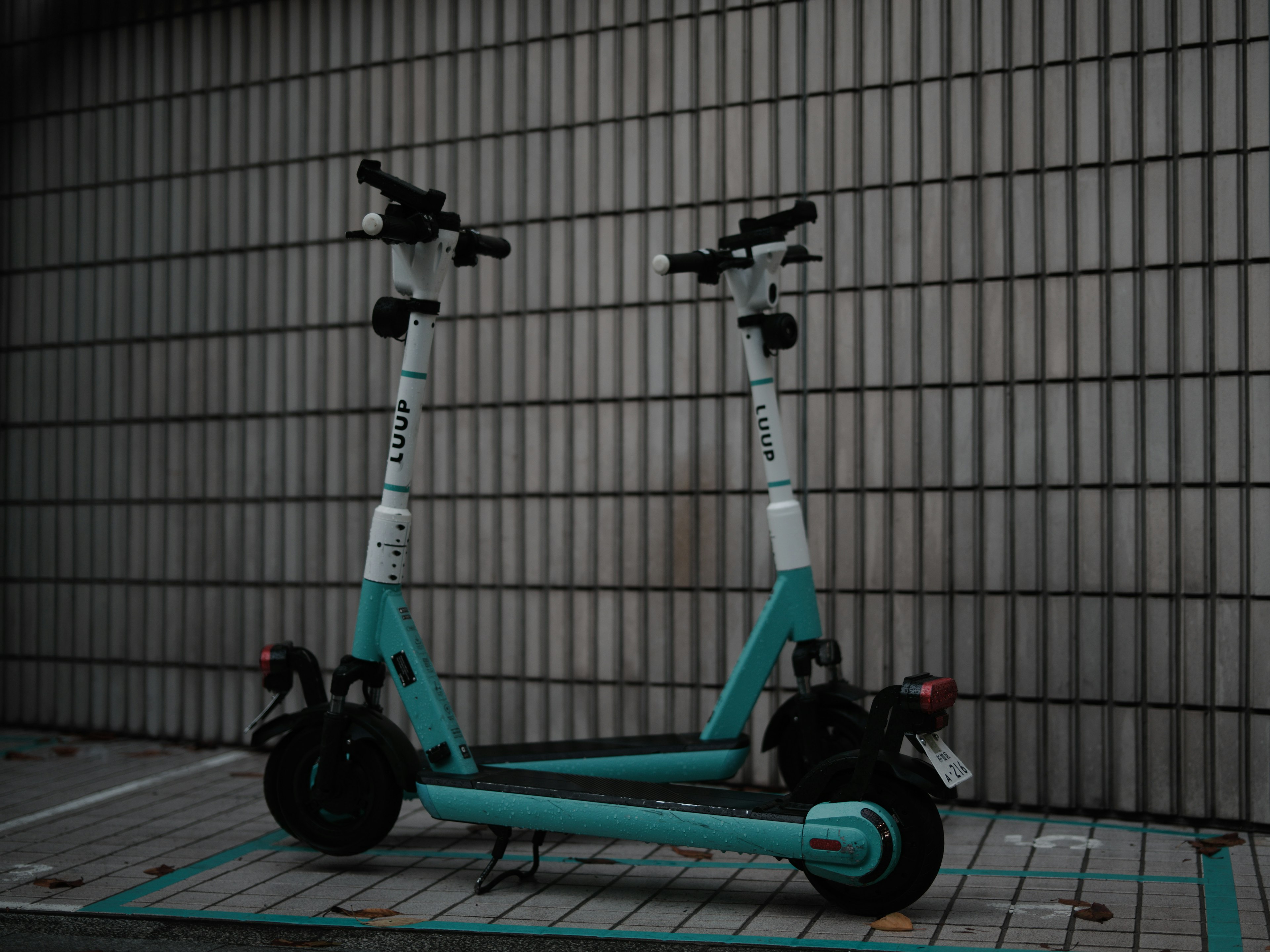 Deux scooters électriques turquoise garés contre un mur carrelé