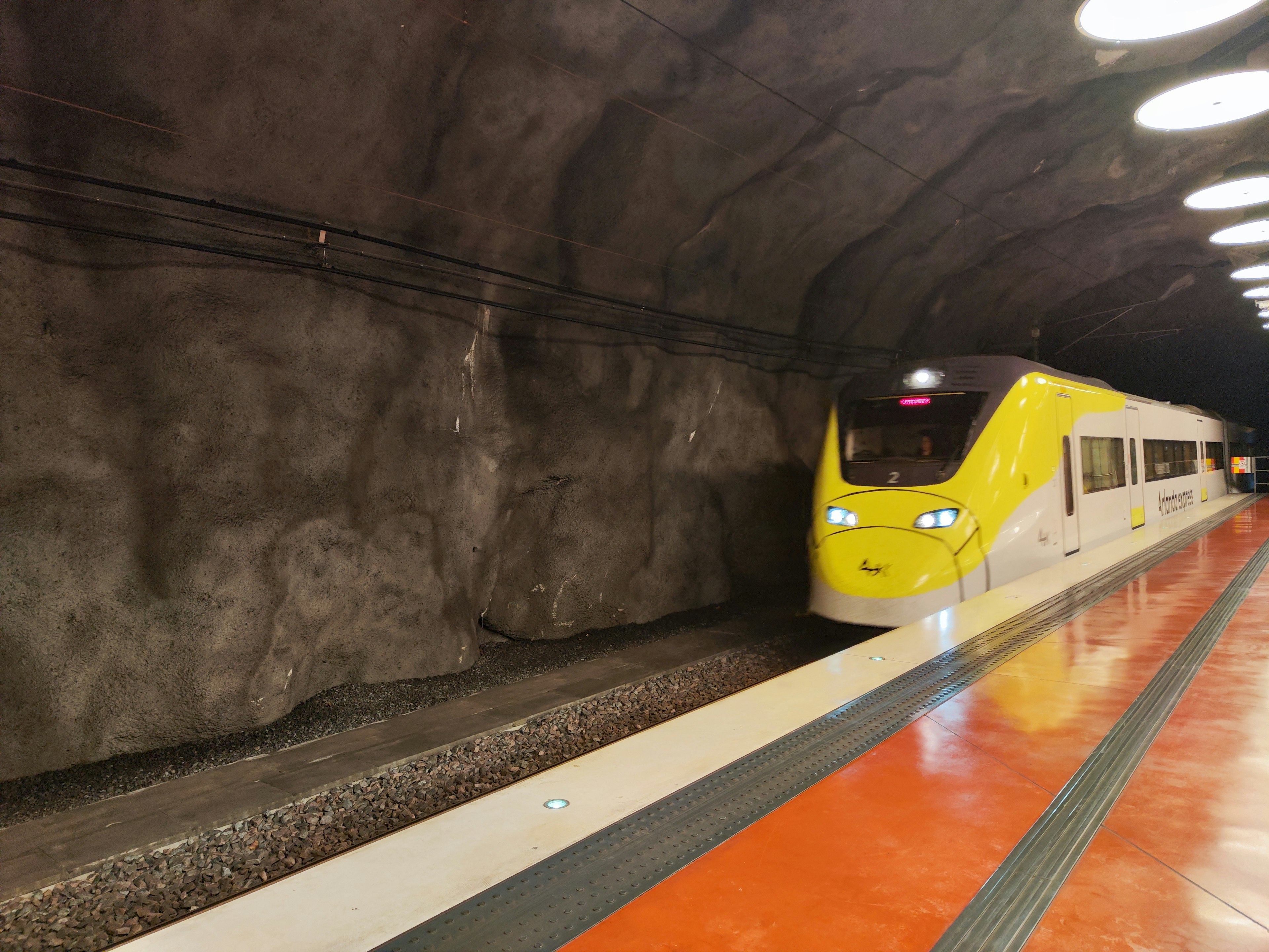 Train jaune arrêté dans un tunnel avec des murs en roche